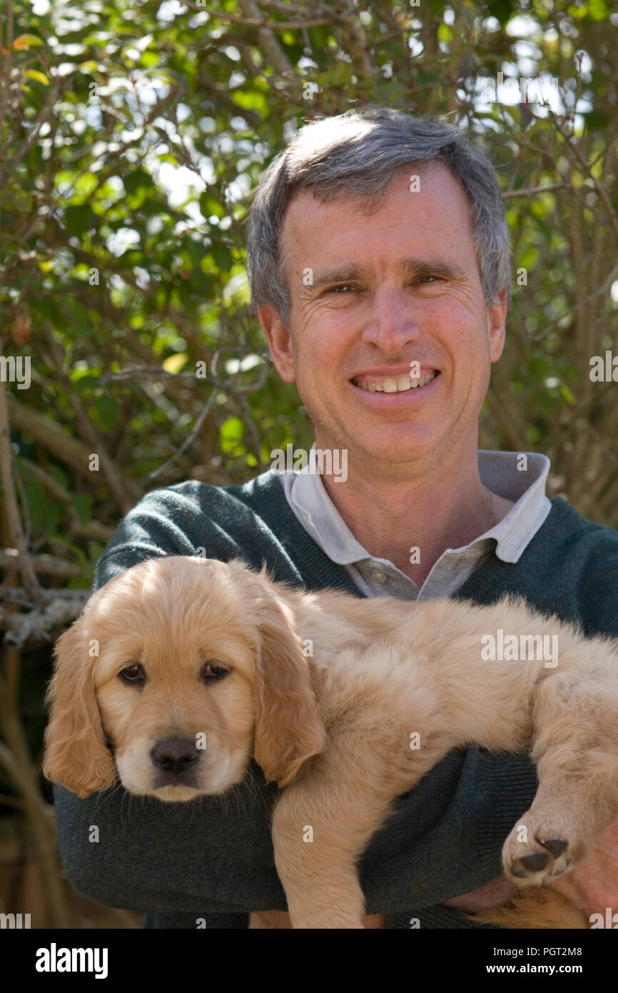 Costitutore tenendo il golden retriever cucciolo che egli ha mantenuto Foto Stock