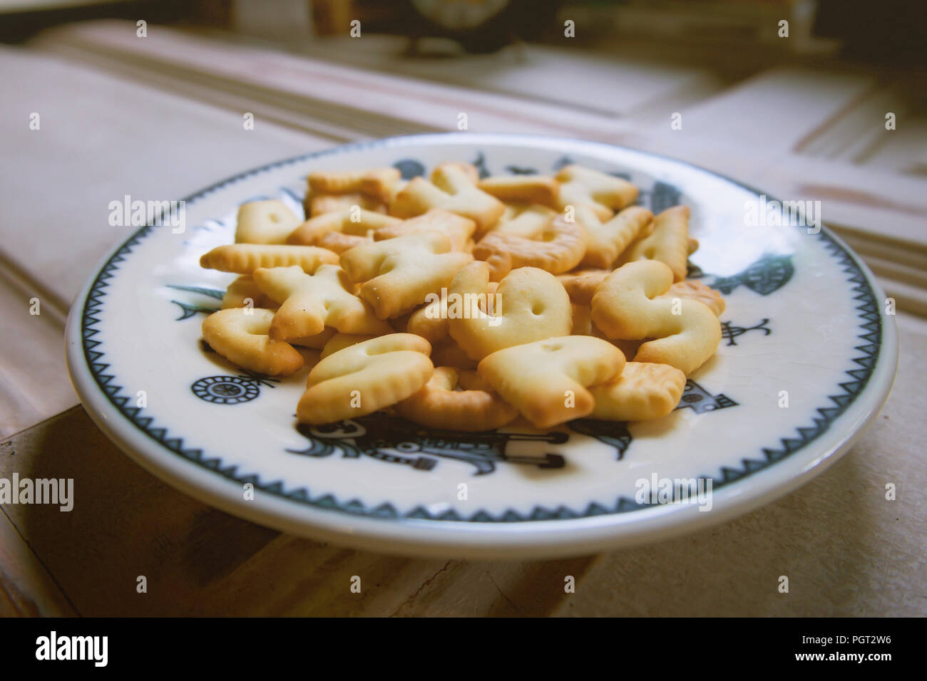 Alfabeto cookie (A-Z) in ceramica bianca piastra sul ripiano di legno a vintage cafe. Foto Stock