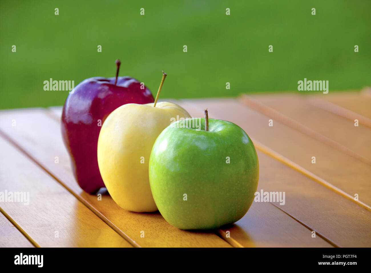 Tre mele su una tabella rossa e Golden Delicious e Granny Smith Foto Stock