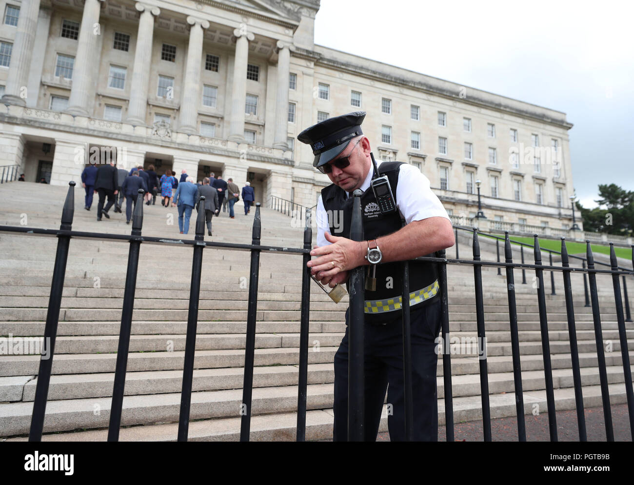 Una guardia di sicurezza blocca le porte fuori gli edifici del Parlamento di Stormont a Belfast come membri della DUP entra nel palazzo dopo una conferenza stampa. Il governo ha riconosciuto la profonda frustrazione del pubblico in Irlanda del Nord come la regione ha raggiunto una pietra miliare indesiderati per non-governance. Foto Stock