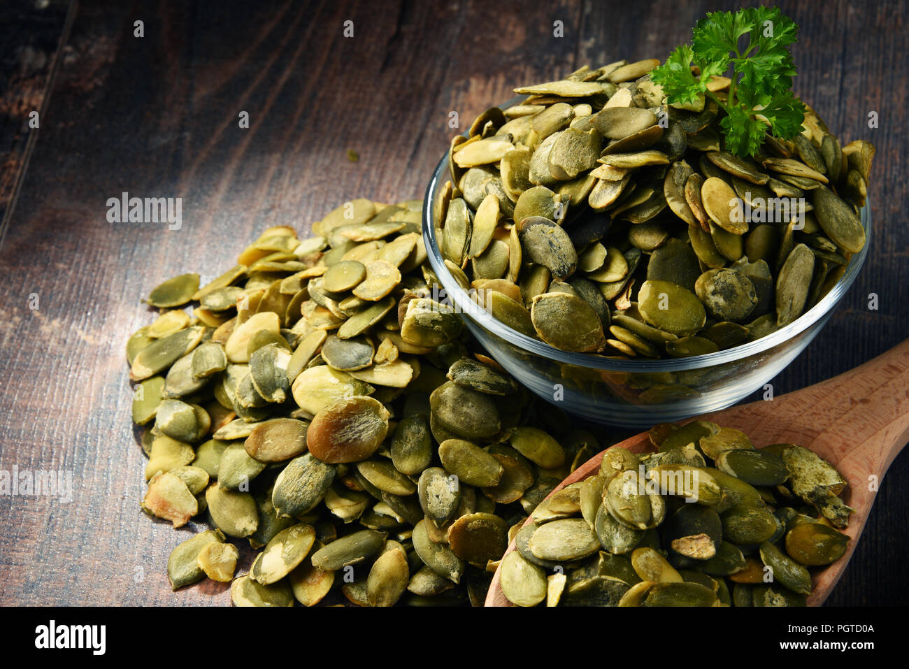 Composizione con una ciotola di semi di zucca su un tavolo di legno. Foto Stock