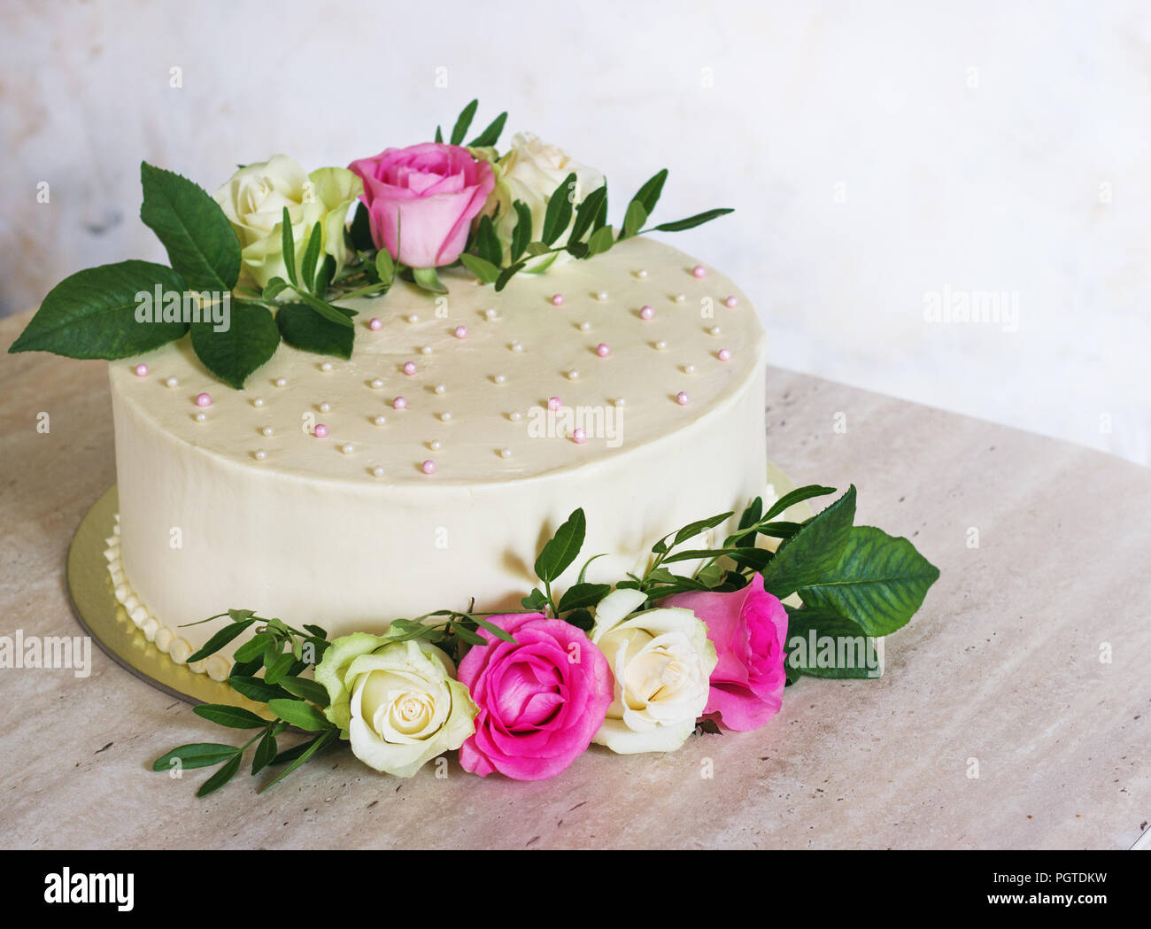 Bella torta di nozze con fiori sulla tavola di marmo e sfondo bianco. Foto Stock