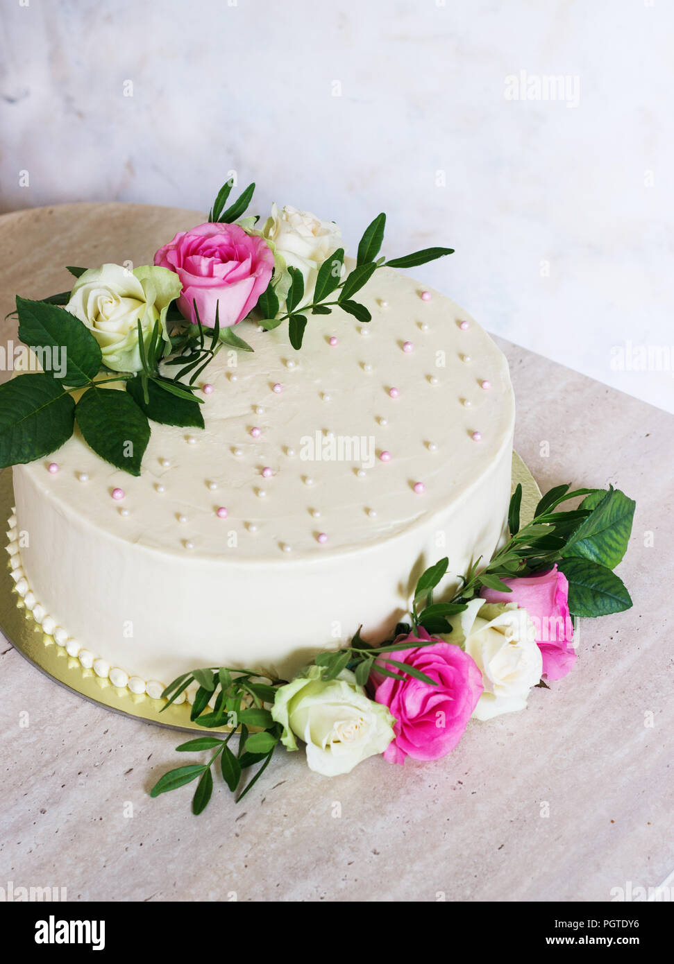Bella torta di nozze con fiori sulla tavola di marmo e sfondo bianco. Foto Stock