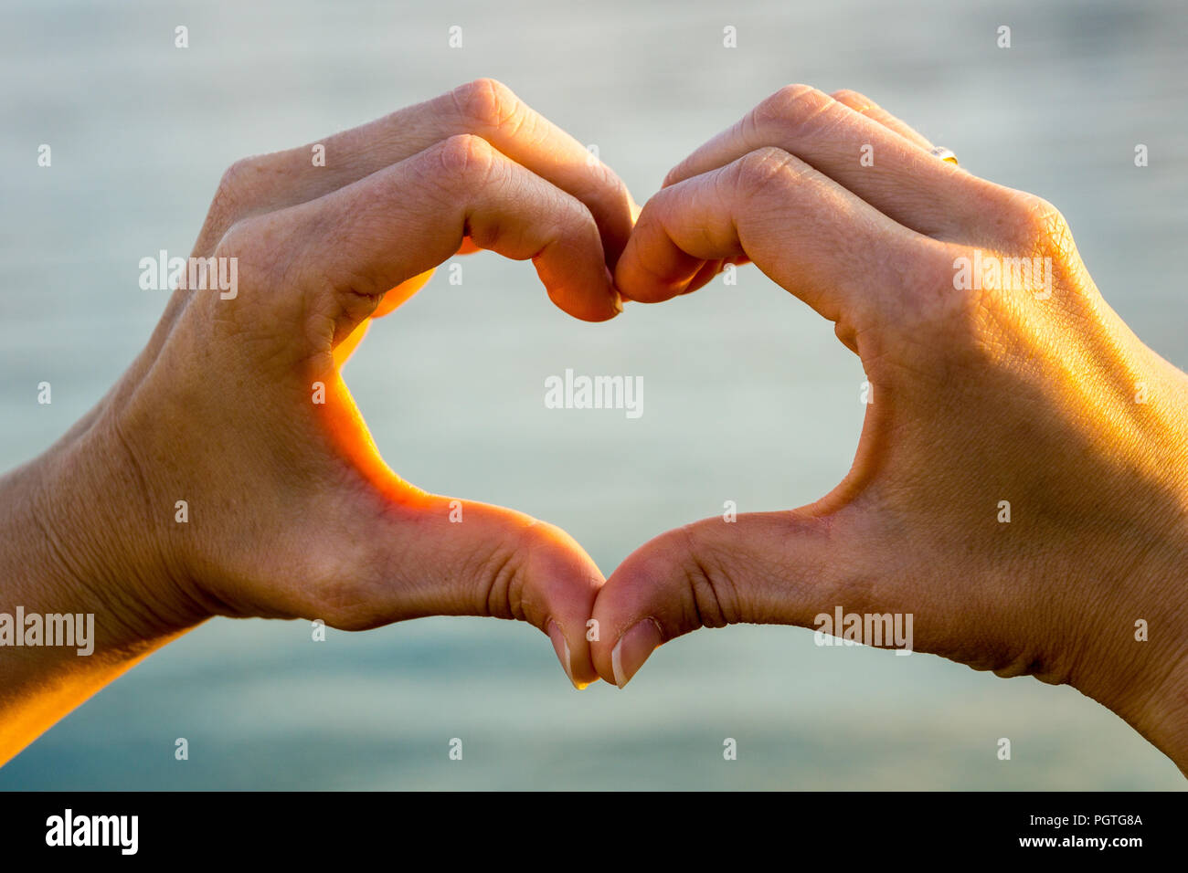 Cuore di amore formata di due mani in luce calda del sole Foto Stock