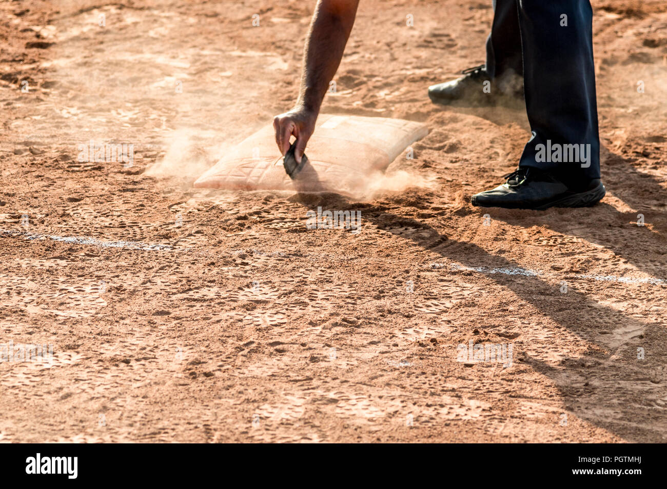 Arbitro pulisce home piastra in un baseball (softball) campo polveroso, con copyspace Foto Stock