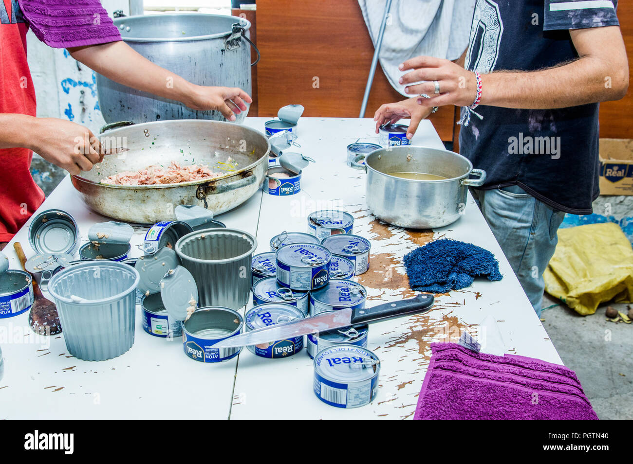 QUITO, ECUADOR, Agosto 21, 2018: la gente in cucina cucina la cena e aprire molte tonno può, all'interno di un rifugio per il popolo venezuelano che sfuggito fr Foto Stock