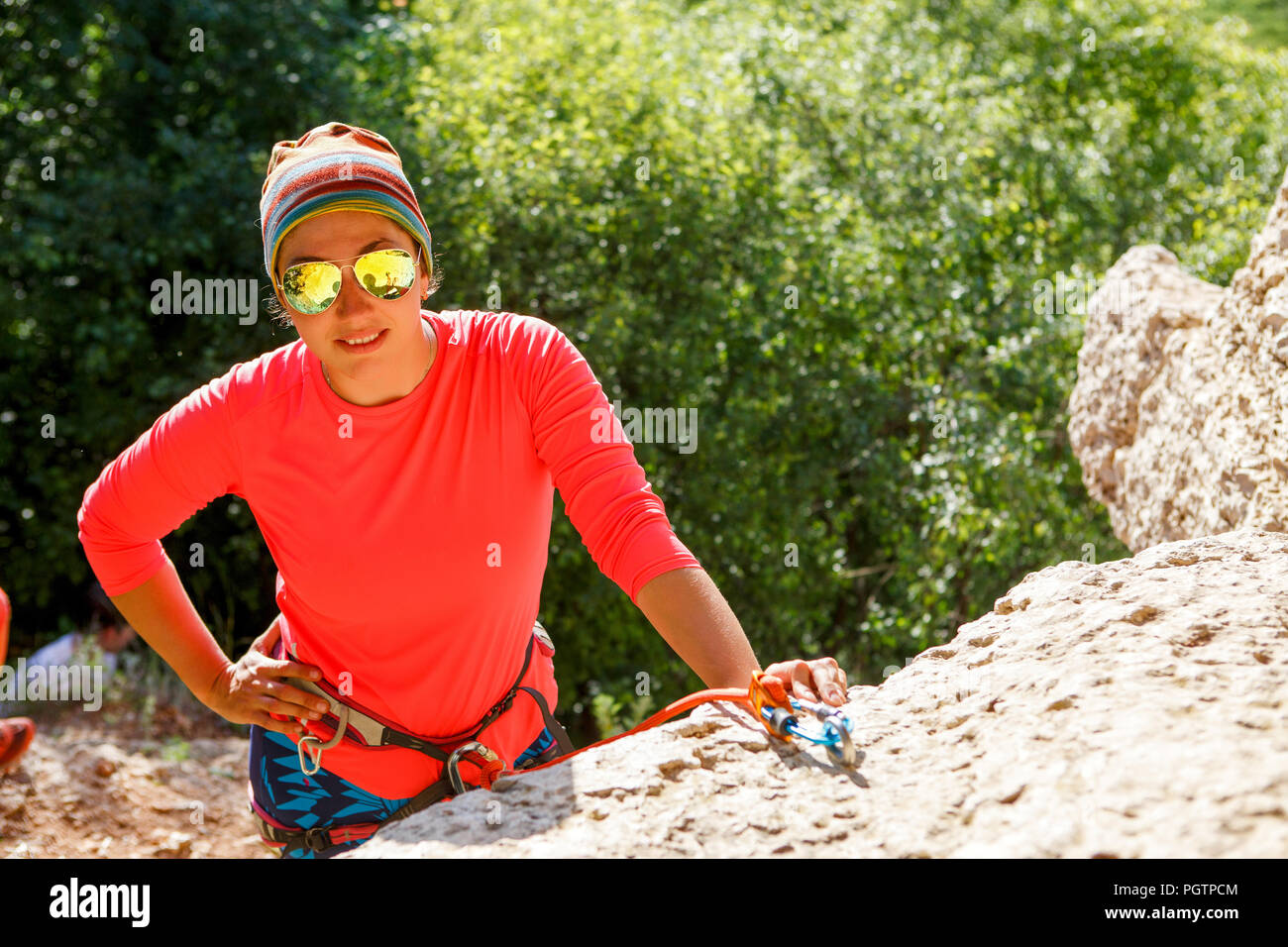 Foto di donna sorridente scalatore indossando occhiali da sole seduto  accanto alla montagna Foto stock - Alamy