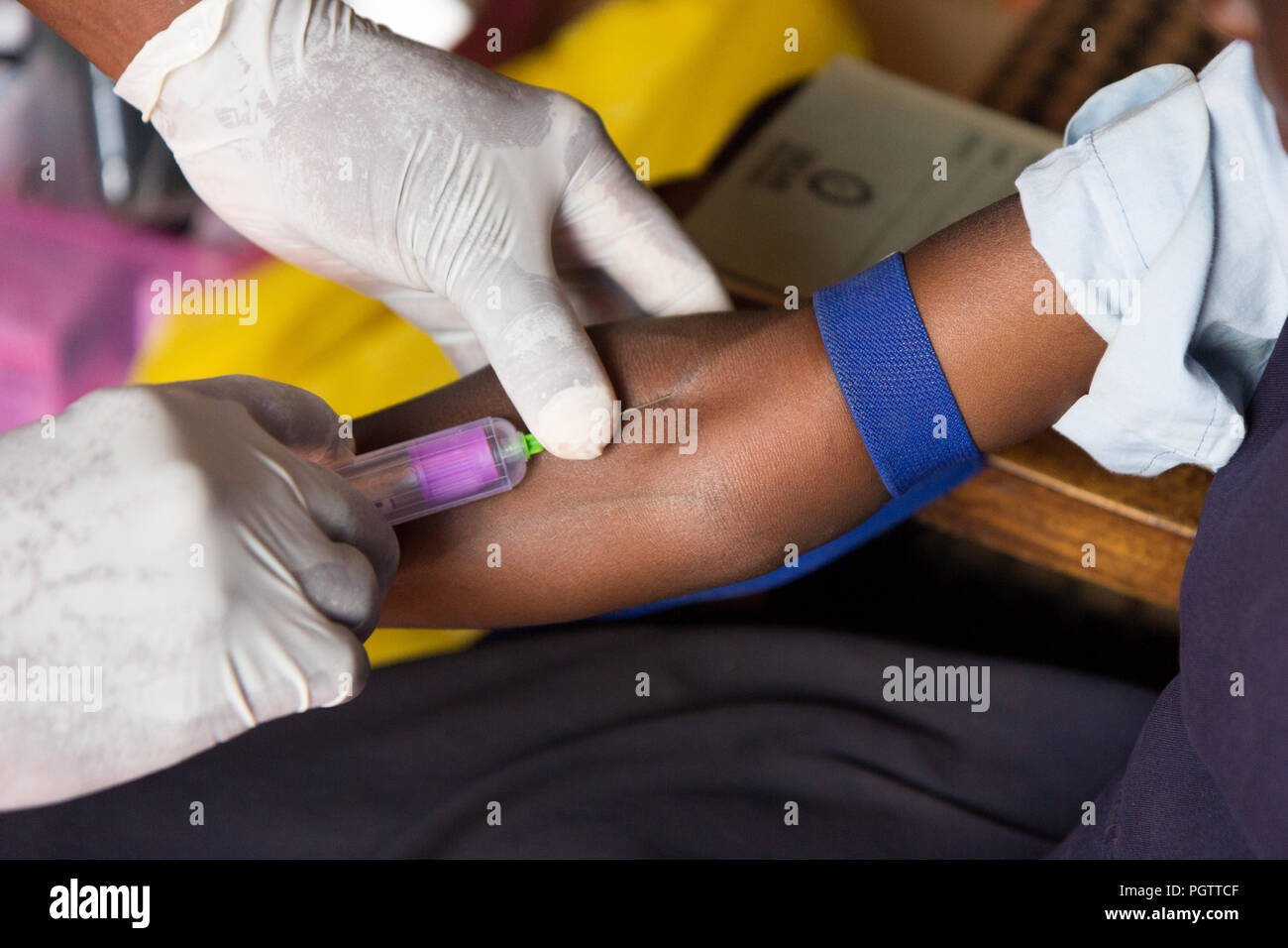 Un lavoratore di salute di assunzione di un campione di sangue dalla vena cubital forando la vena e la raccolta di sangue in una provetta di test sotto pressione negativa Foto Stock