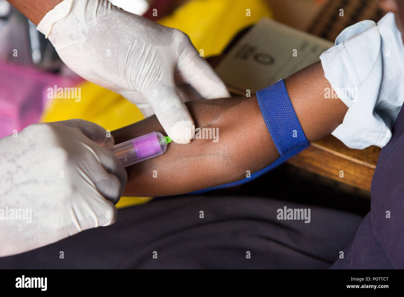 Un lavoratore di salute di assunzione di un campione di sangue dalla vena cubital forando la vena e la raccolta di sangue in una provetta di test sotto pressione negativa Foto Stock