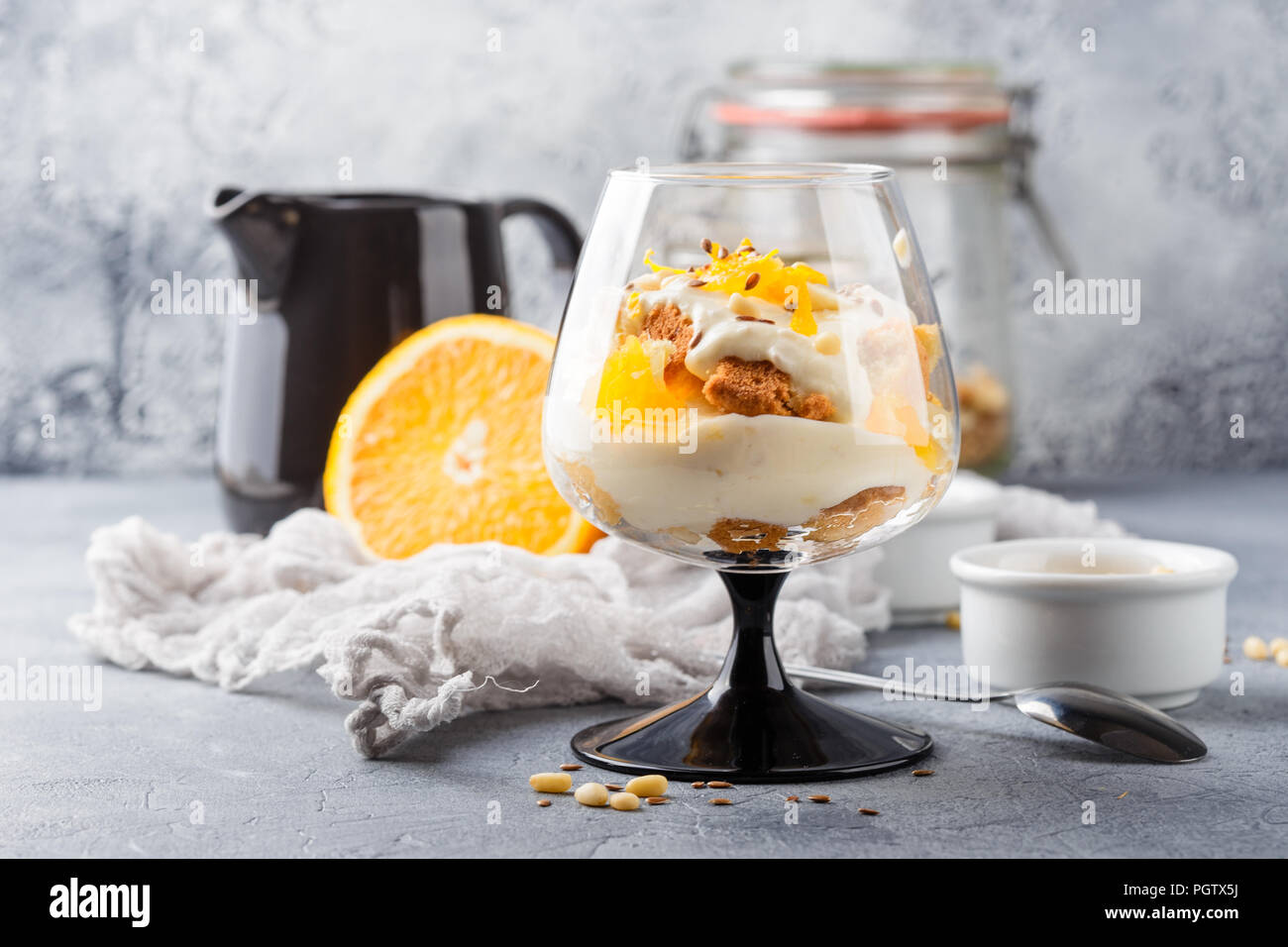 Vetro con una sana in casa dessert stratificata scherzare con Orange, biscotti, yogurt e cereali Foto Stock