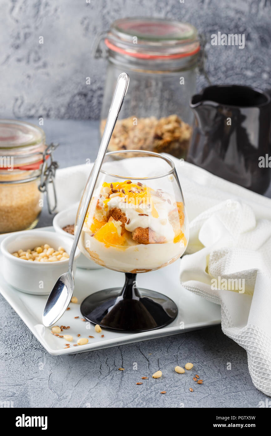 Vetro con una sana in casa dessert stratificata scherzare con Orange, biscotti, yogurt e cereali Foto Stock
