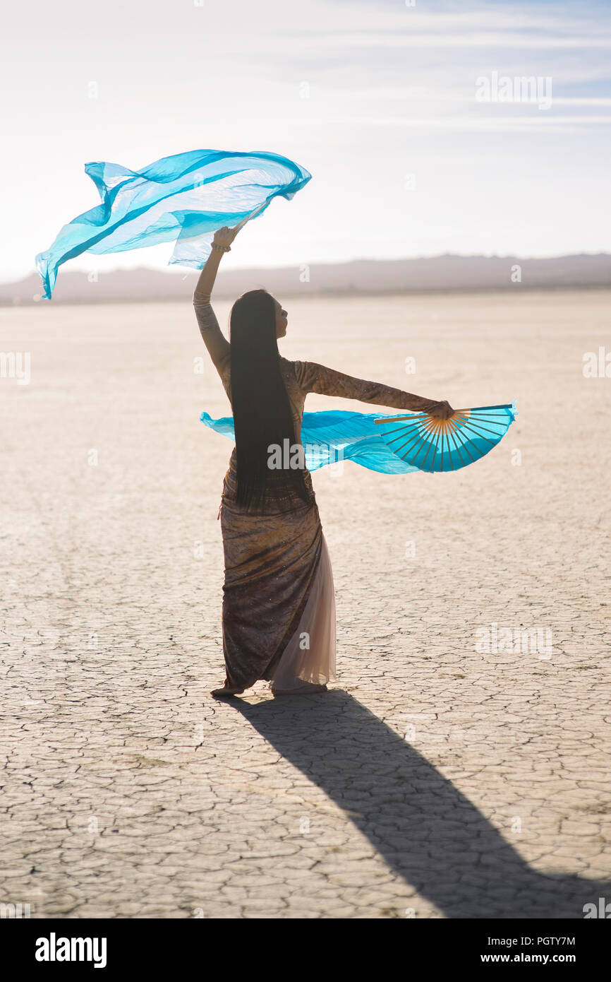 Una danzatrice del ventre con bandiere di seta ballato nel deserto Foto Stock