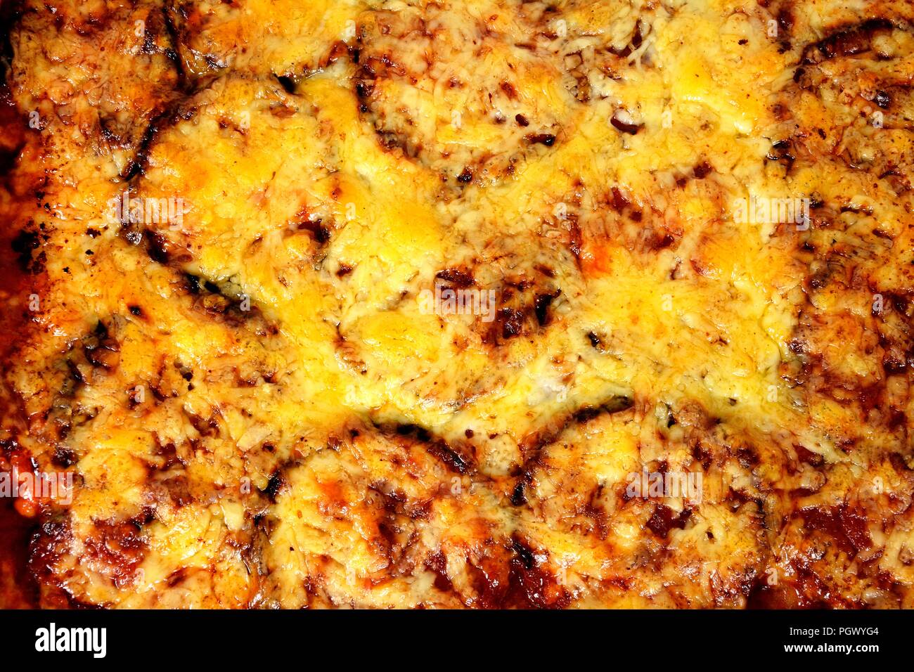 Strati al forno di melanzana, formaggio e pomodoro condito con formaggio fuso sfondo alimentare. Foto Stock
