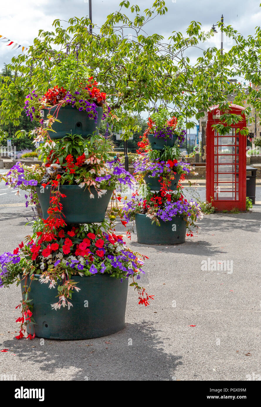 Centro città piantatrici di fiori in Baildon, nello Yorkshire, Inghilterra. Le composizioni floreali sono in una zona pedonale vicino a un telefono rosso scatola. Foto Stock