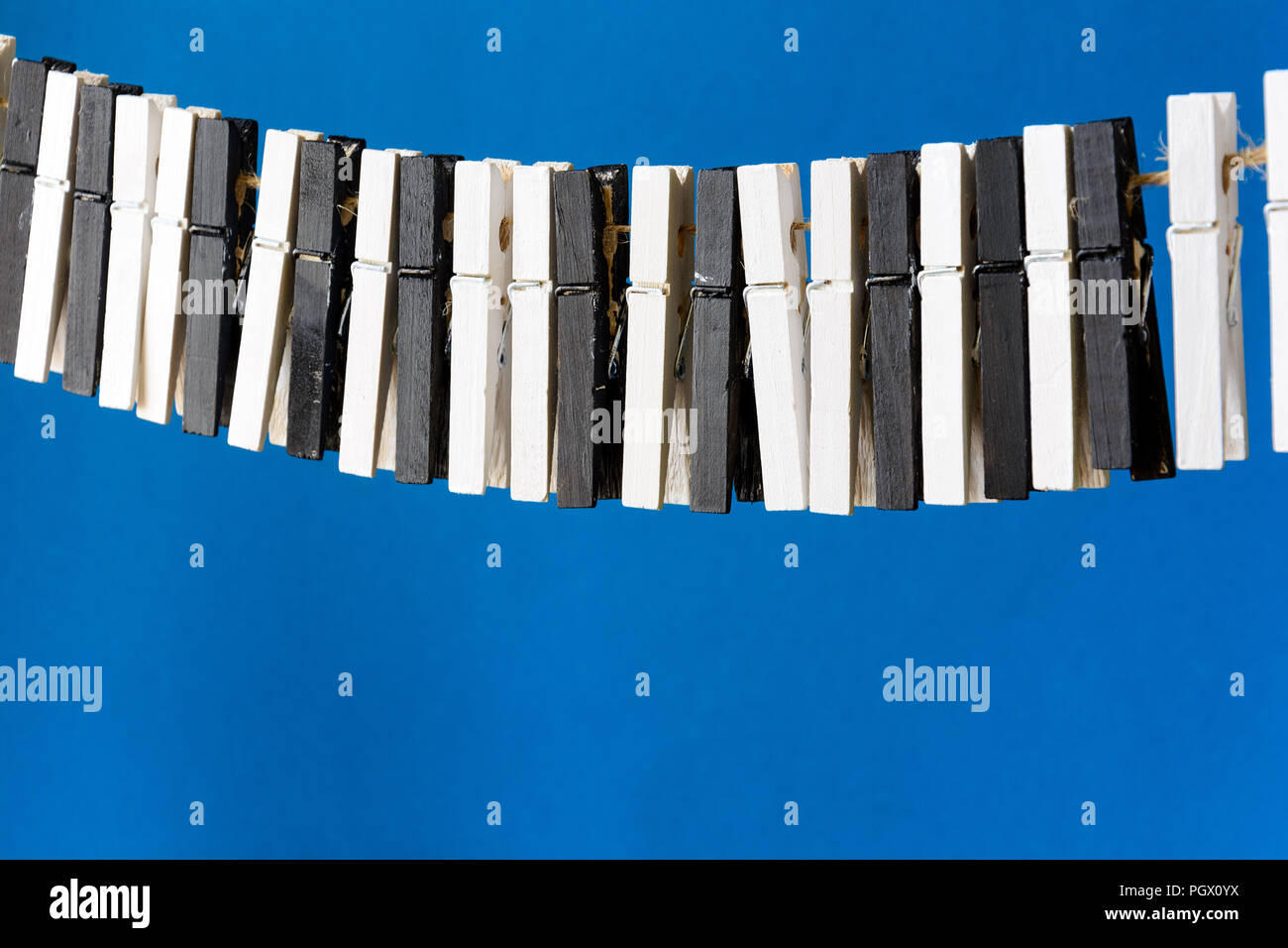 Close-up di una donna di mano suonare il pianoforte immaginario realizzati dai vestiti pin su carta blu sullo sfondo. Sognare di musica. Foto Stock