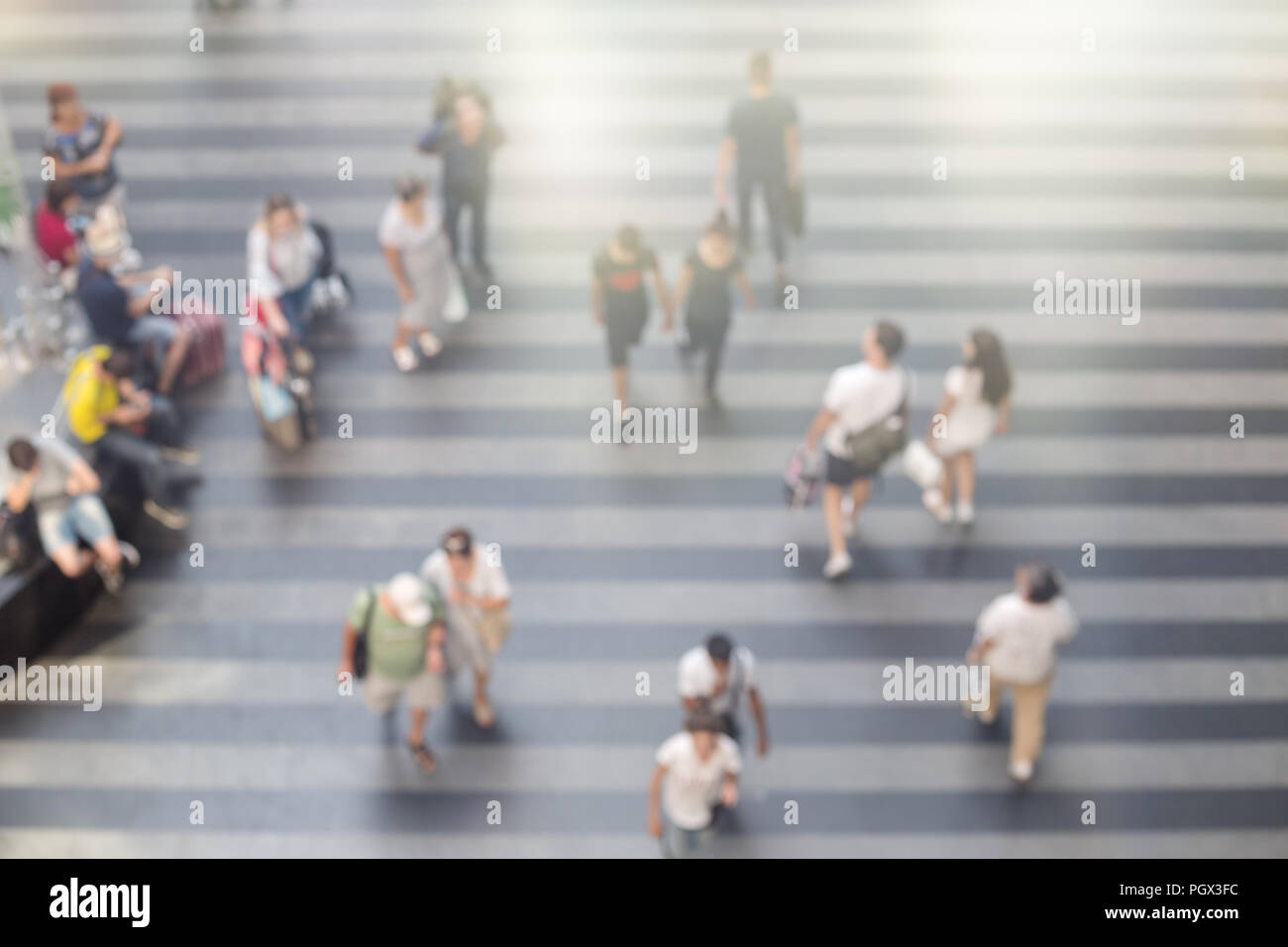 Abstract offuscata la gente a piedi in aeroporto o stazione ferroviaria area con pavimento striato. Orario estivo, vista dall'alto. Foto Stock