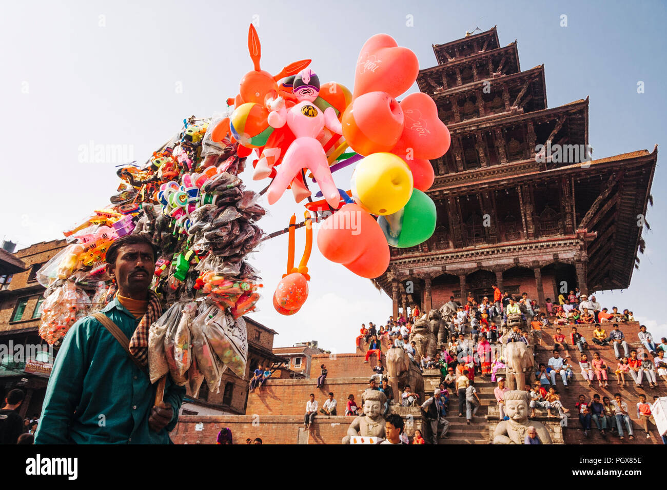 Bhaktapur, Valle di Kathmandu, Bagmati, Nepal : un fornitore di palloncini sorge come una folla di curiosi si raccoglie in corrispondenza dei gradini del tempio Nyatapola a Taumadh Foto Stock