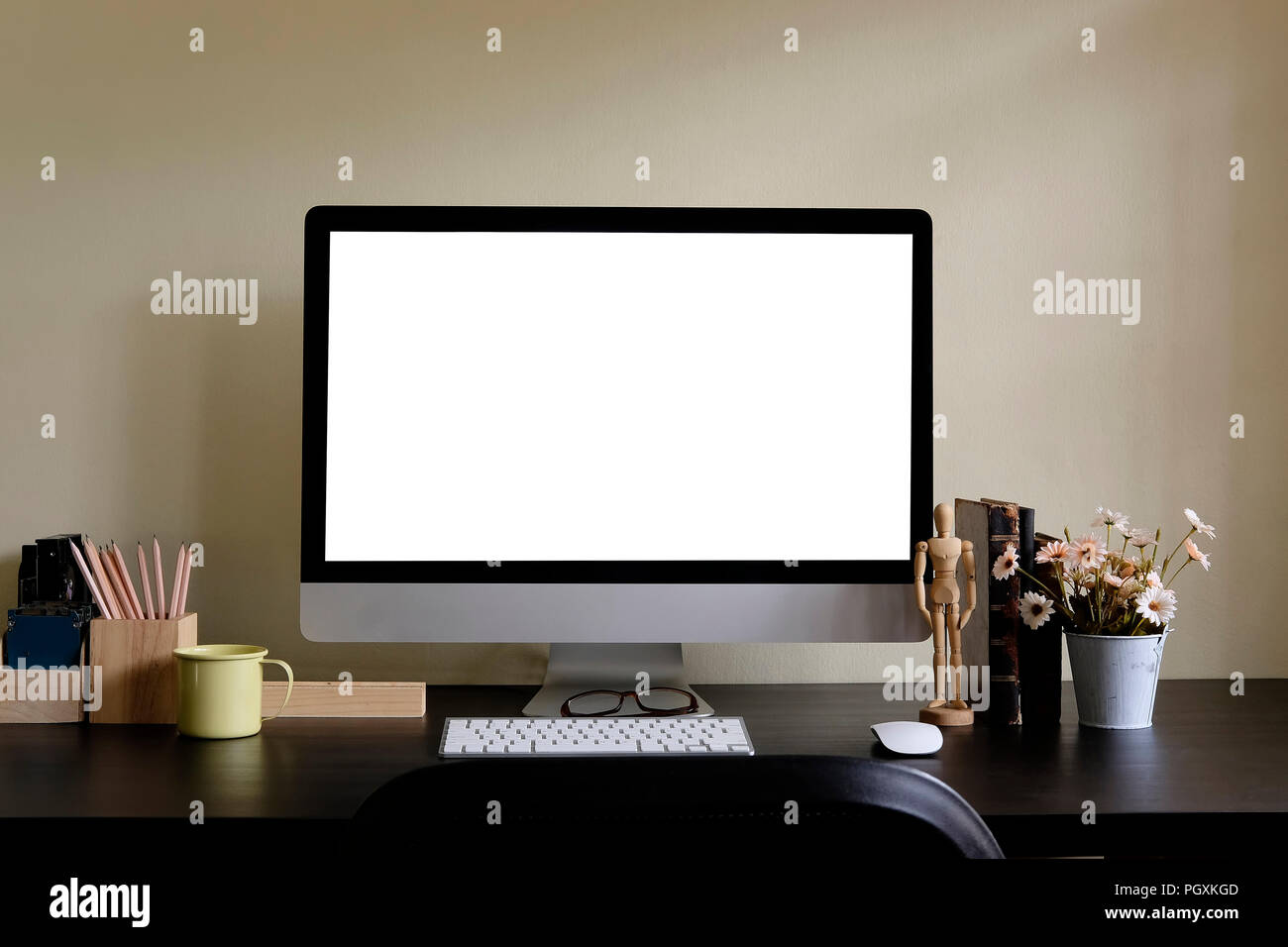 Area di lavoro con un display di computer e strumenti di office su tavola nera. Computer desktop isolato sullo schermo. Moderno banco creative con fiore . Vista frontale. Foto Stock
