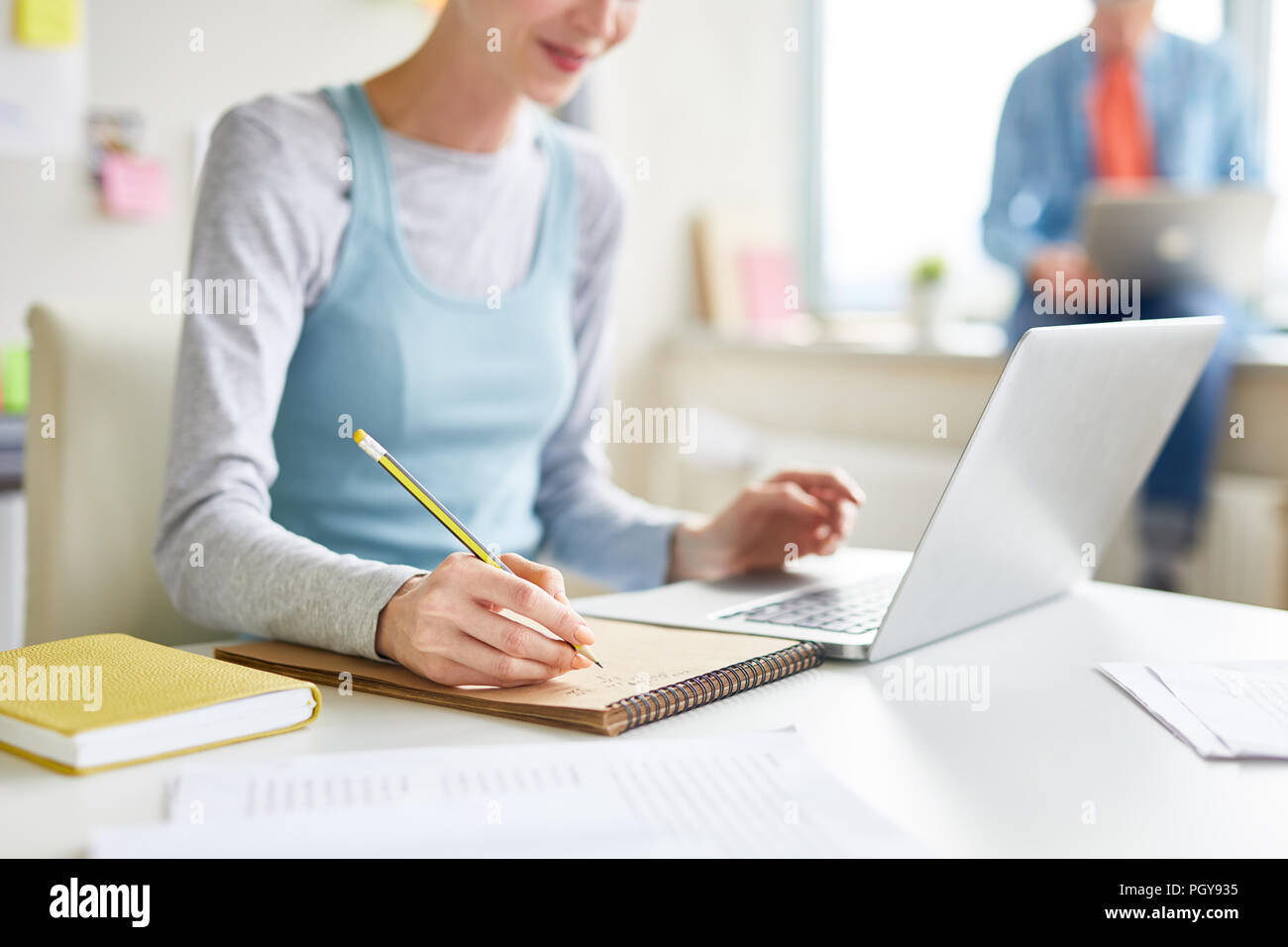 Close-up della ragazza seduta a tavola e utilizzando computer portatile mentre riassumendo articolo online in classe Foto Stock