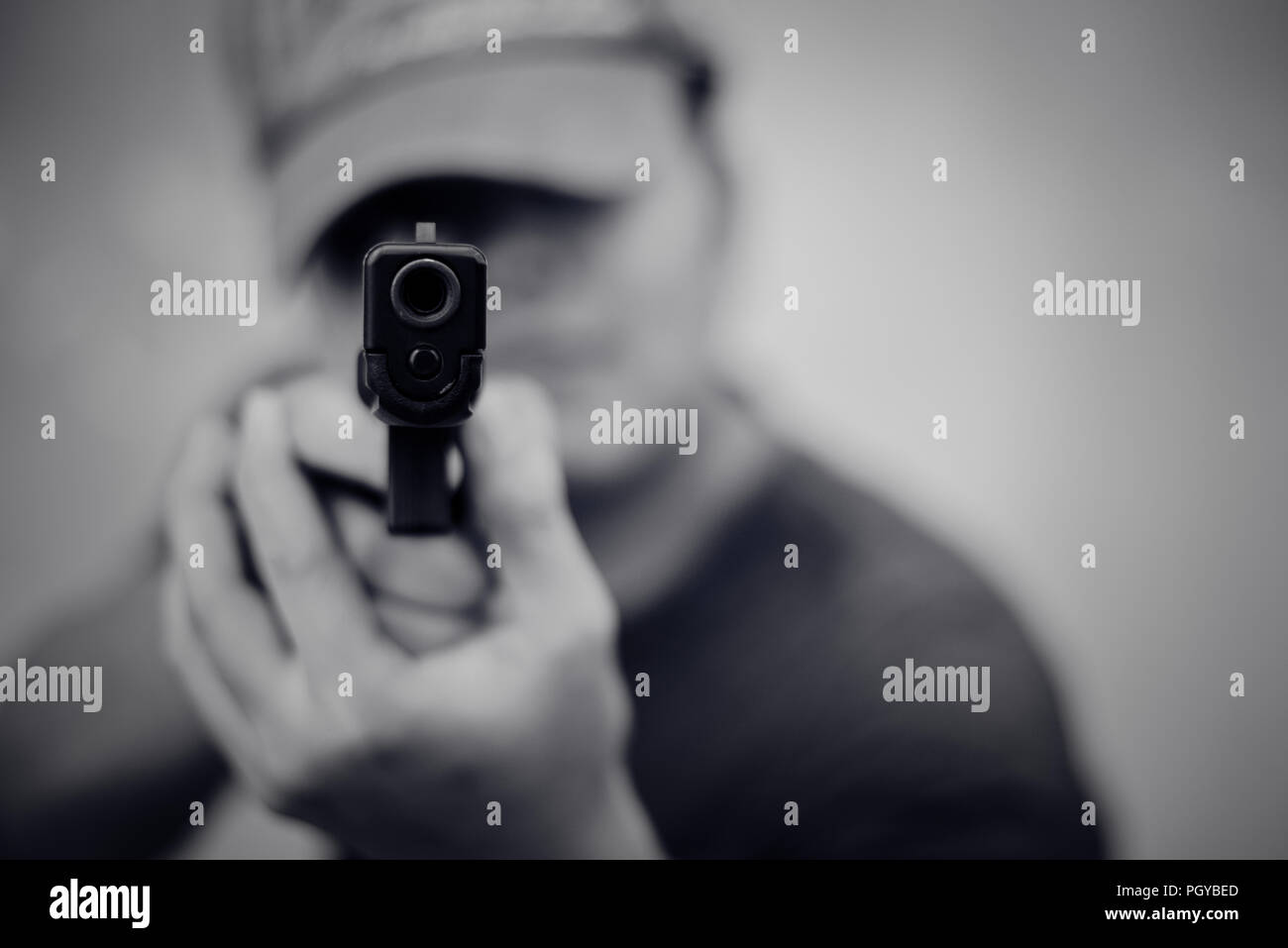 Uomo che ha di mira la pistola e pronti a sparare su vista frontale. Persone e di pericolose armi concetto. Penale e il tema della sicurezza. Cooperazione di polizia e rapinatore tema. Un fuorilegge Foto Stock