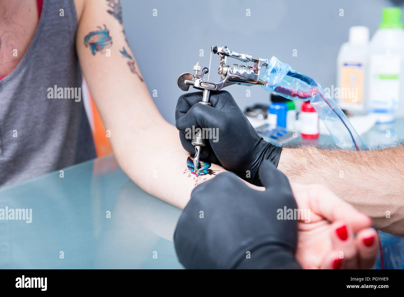 Close-up delle mani di un esperto tattoo artist indossando guanti neri durante la configurazione di una macchina sterile per tatuare in un moderno studio Foto Stock