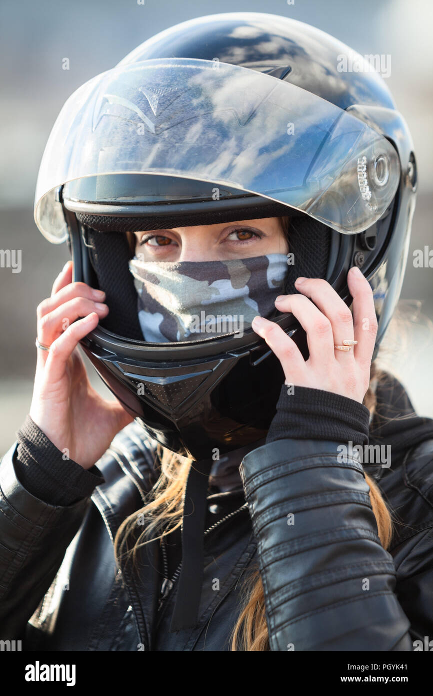 Vista ravvicinata alla donna caucasica motociclista crash che indossa il casco nero sul suo capo Foto Stock