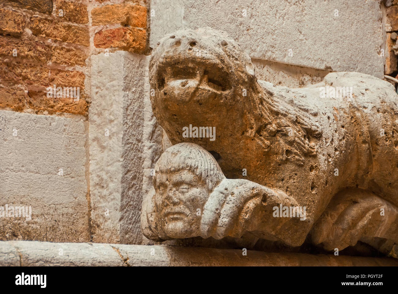 Lion o Monster tenendo testa umana con zampe, antica statua medievale su una parete nel centro storico di Venezia Foto Stock