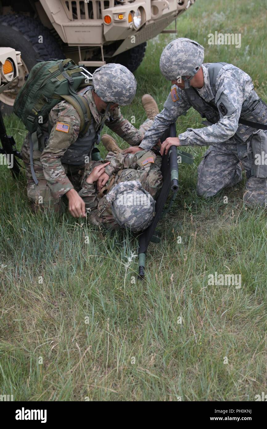 Un U.S. Army Medic da 1077th azienda medica (massa ambulanza), Kansas esercito nazionale Guard (KSARNG), e un'U.S. Soldato dal 731st Transportation Company, KSARNG, posizionare una simulazione di incidente su una barella in preparazione per evacuazione medica, durante un incidente di Massa evento di formazione a sostegno del Golden Coyote, Custer State Park, S.D., 16 giugno 2018. Il Golden Coyote è un esercizio a tre-fase, scenario di esercizio di condotta condotta in Black Hills del Sud Dakota e Wyoming, quali comandanti permette di concentrarsi sulla missione requisiti essenziali per lo svolgimento delle attività e le attività del guerriero e punte di battaglia. Foto Stock