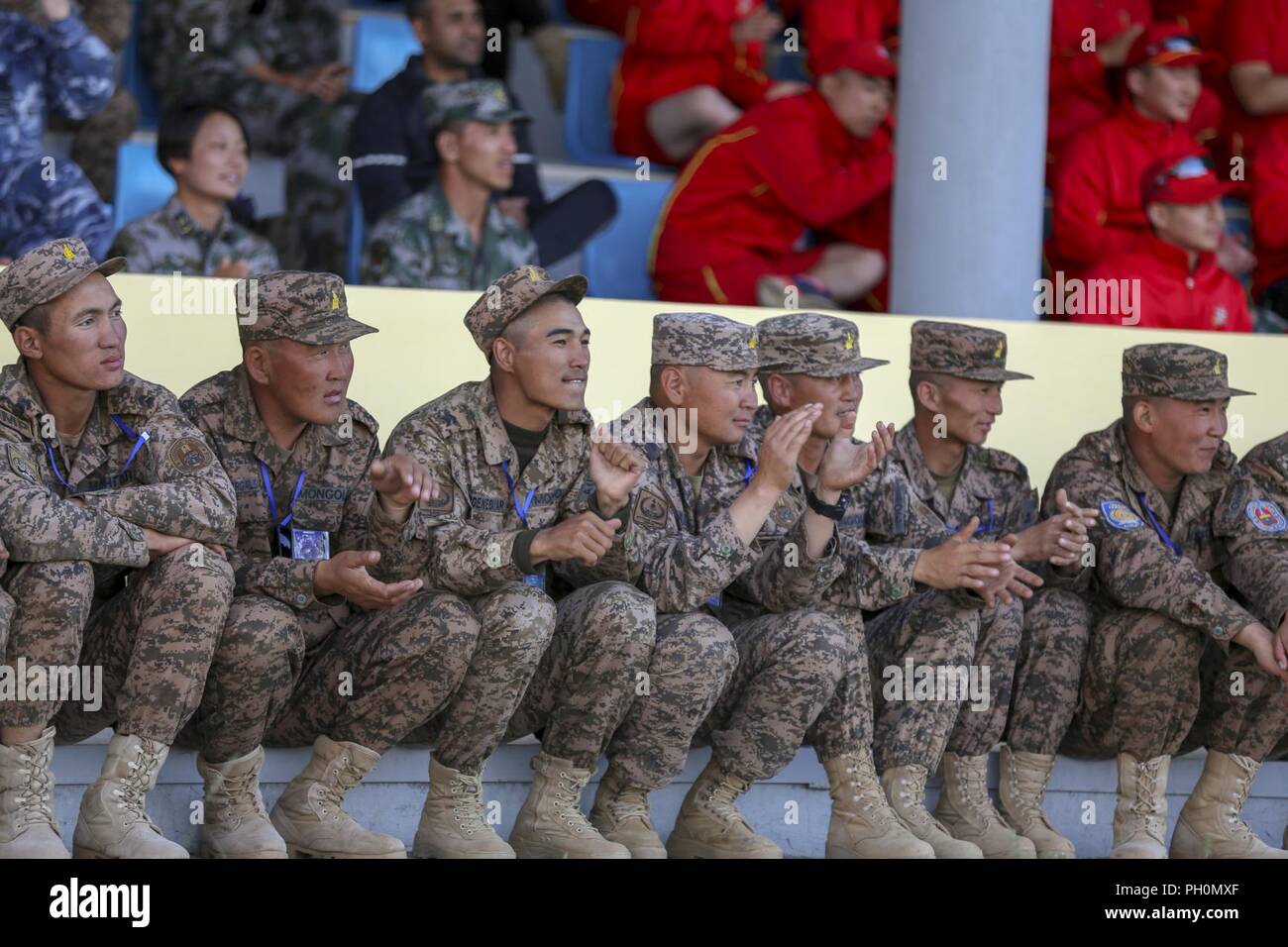 Membri della Mongolia le forze armate tifare per una banda mongola e ensemble di danza insieme ai colleghi i caschi blu da nazioni straniere durante Khaan ricerca 2018 a cinque colline Area Formazione, Mongolia, Giugno 15. KQ18 è regolarmente programmate, multinazionale esercizio co-sponsorizzato da U.S. Pacifico Comando e ospitato annualmente da Mongolo Forze Armate. È il più recente di una serie continua di esercizi pensati per promuovere pace e alla sicurezza della regione. Questo anno di esercizio segna il Sedicesimo anniversario dell'evento di formazione. Foto Stock