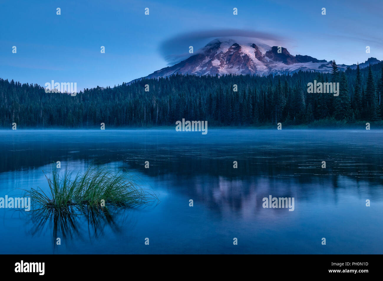 Mount Rainier con cloud lenticolare all'alba dalla riflessione lago; il Parco Nazionale del Monte Rainier, Washington. Foto Stock