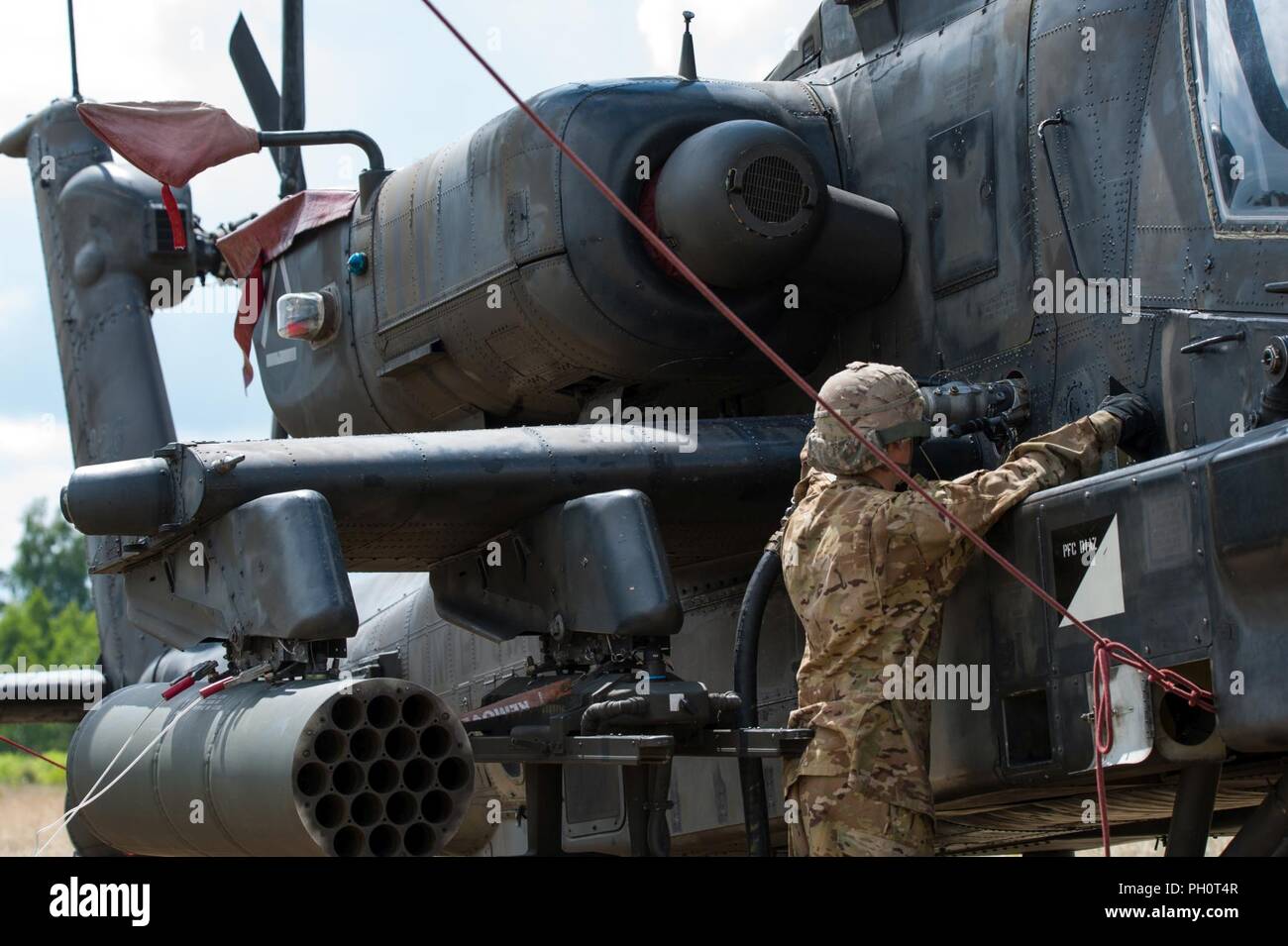 Spc. Christopher Castillo assegnato alla Task Force Viper° Battaglione, 3° Reggimento di aviazione, XII Combattere la Brigata Aerea refuels AH-64 elicotteri Apache durante lo sciopero di Saber 18 esercizi a Bemowo Piskie Area Formazione in Orzysz, Polonia, 14 giugno 2018. Foto Stock