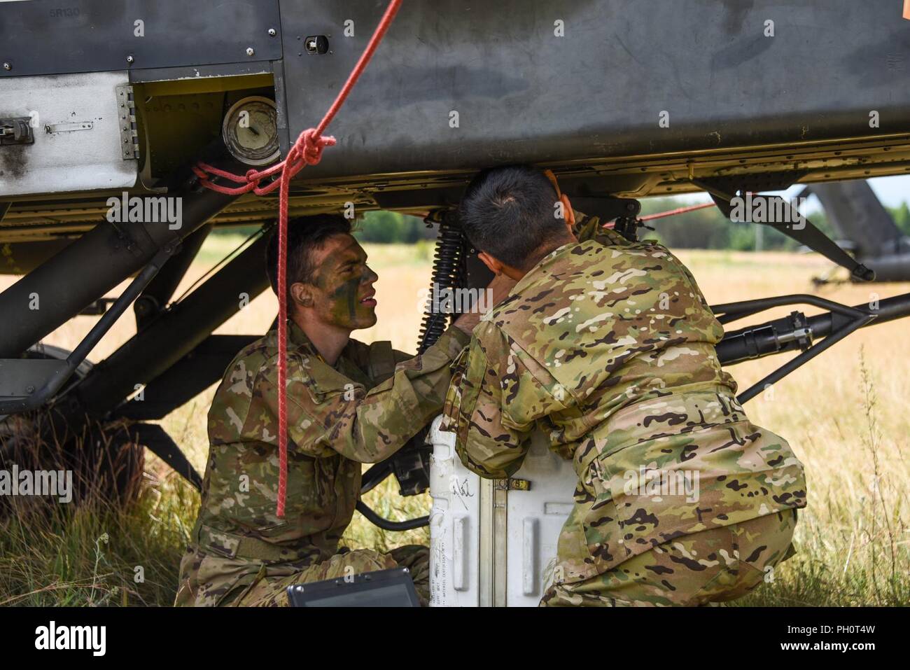 Sgt. Nathan Choi e PFC. Matteo Hanneman assegnato alla Task Force Viper° Battaglione, 3° Reggimento di aviazione, XII Combattere la Brigata Aerea effettuare manutenzione su AH-64 Apache elicottero durante lo sciopero di Saber 18 esercizi a Bemowo Piskie Area Formazione in Orzysz, Polonia, 14 giugno 2018. Foto Stock