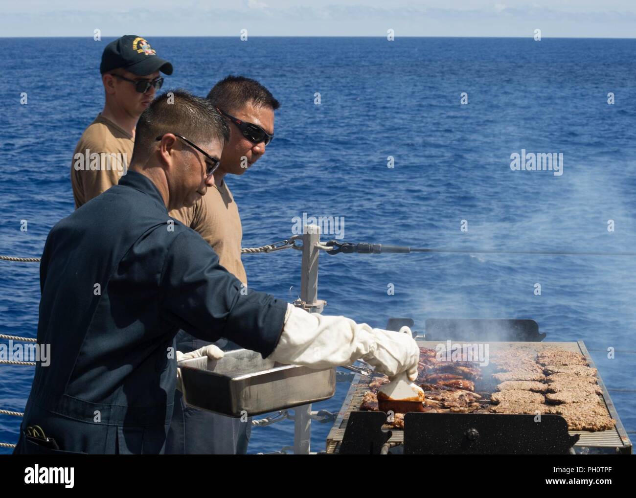 Oceano Pacifico (20 giugno 2018) Chief Fire Controlman Andrew Molina, di Honolulu, a sinistra e a capo di Boatswain Mate John Torres, di Long Beach, California, uomo una griglia durante un acciaio picnic sulla spiaggia a bordo guidato-missile destroyer USS William Lawrence (DDG 110). USS William P. Lawrence è operante negli Stati Uniti La terza area della flotta di responsabilità condurre le qualifiche e le operazioni di routine durante una prevista in corso. Foto Stock