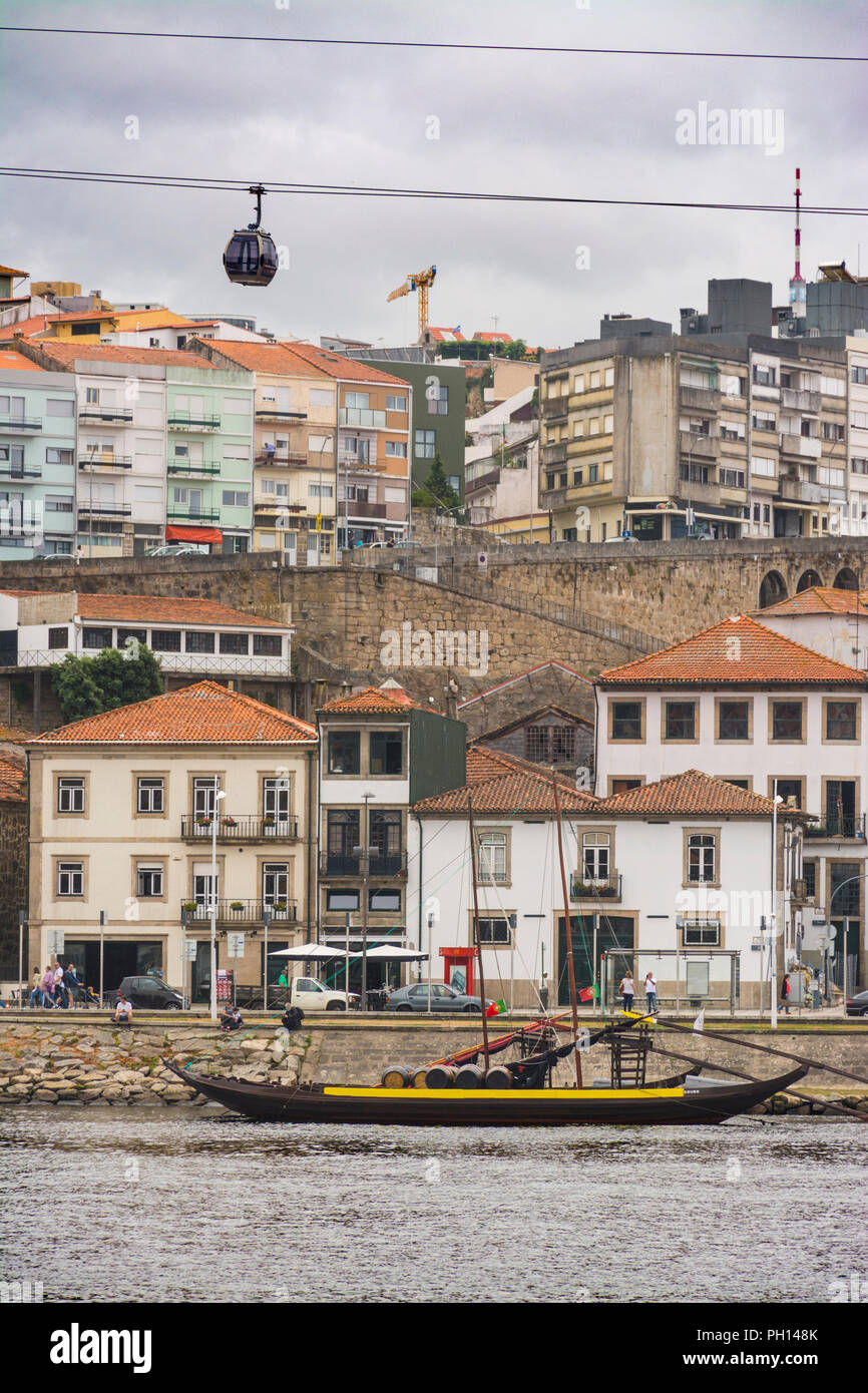 Funivia sopra i magazzini e le cantine di Gaia, con una tradizionale barca per il commercio del vino ormeggiata sul fiume Douro. Porto, Portogallo Foto Stock