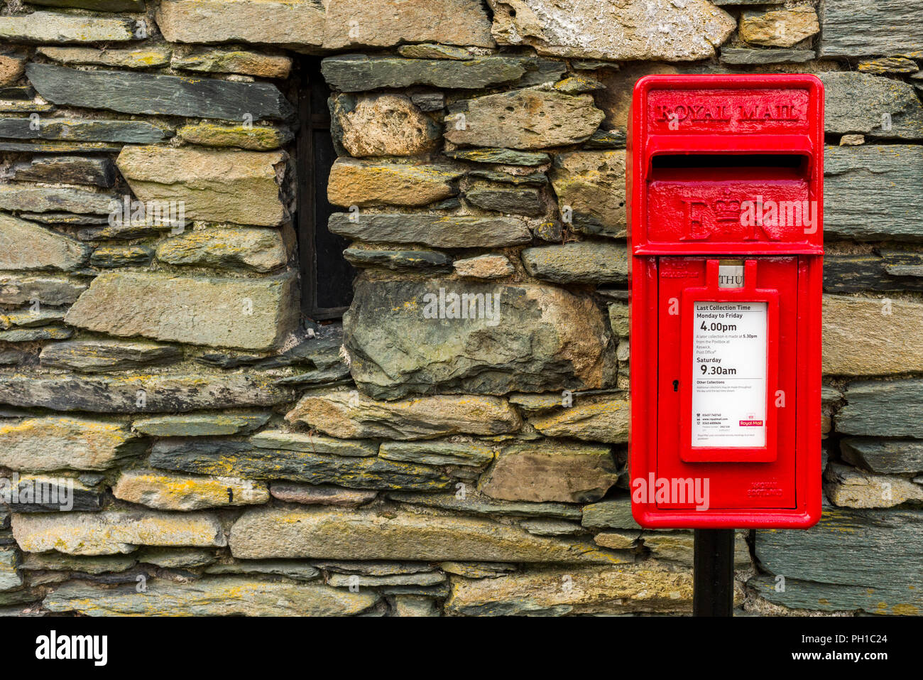 Un rosso post box accanto a un muro di pietra a Grange nel Parco Nazionale del Distretto dei Laghi, Cumbria, Inghilterra. Foto Stock