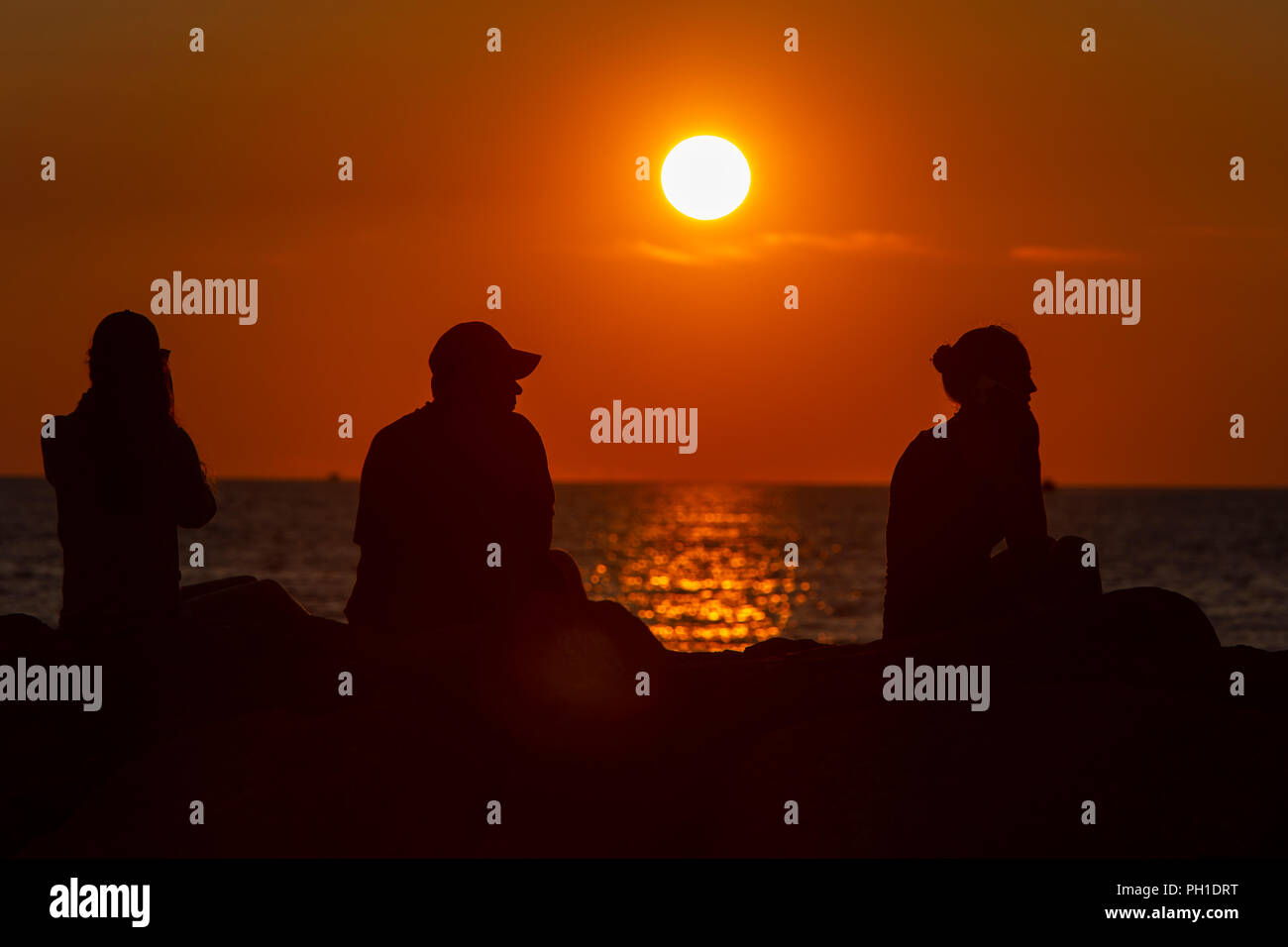 Persone sedersi sul pontile e guardare il tramonto sopra la vigna del suono a Menemsha Beach in Chilmark, Massachusetts di Martha's Vineyard. Foto Stock