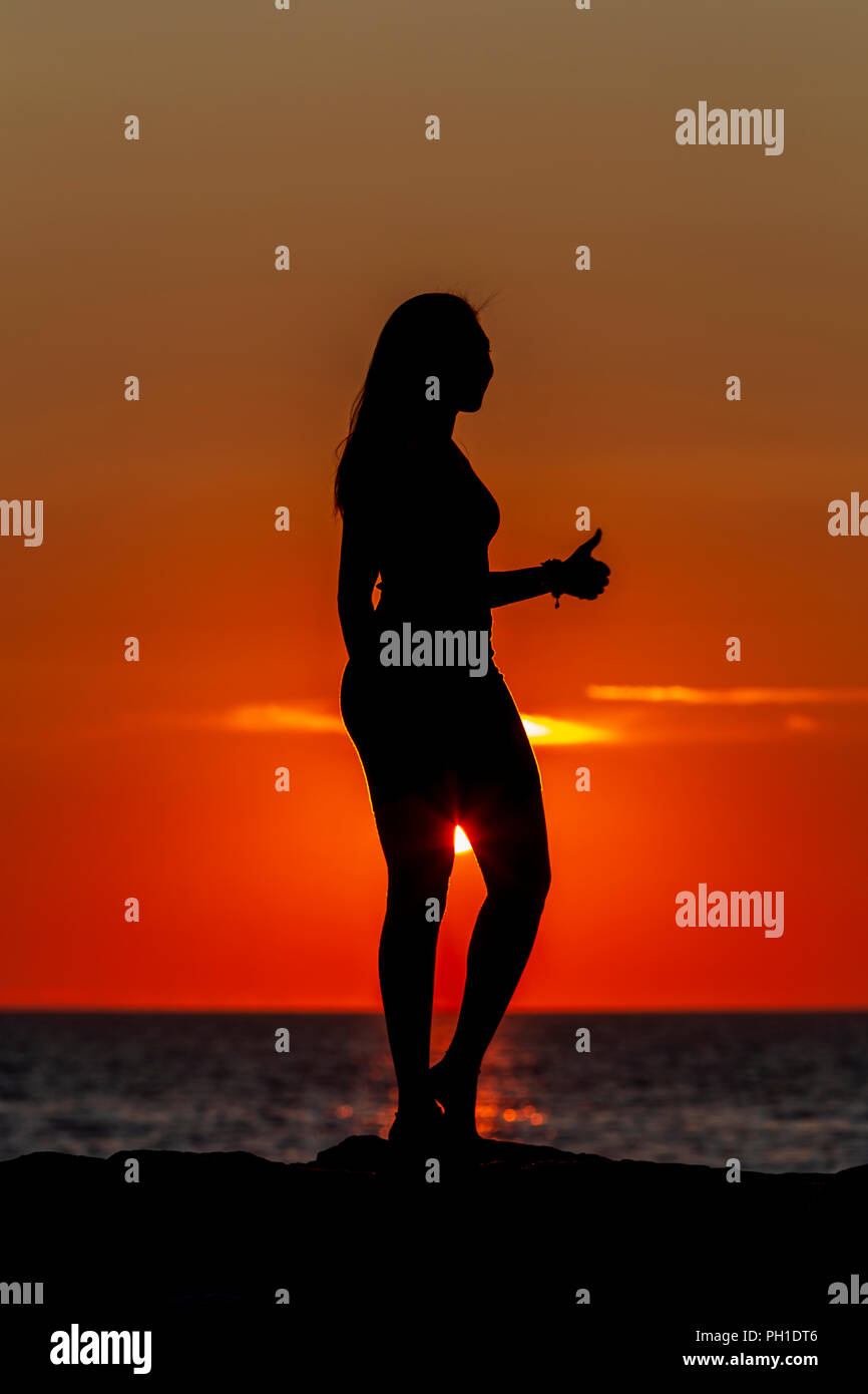 Una donna dà un 'pollice in alto" mentre si stagliano al tramonto sul pontile a Menemsha Beach in Chilmark, Massachusetts di Martha's Vineyard. Foto Stock