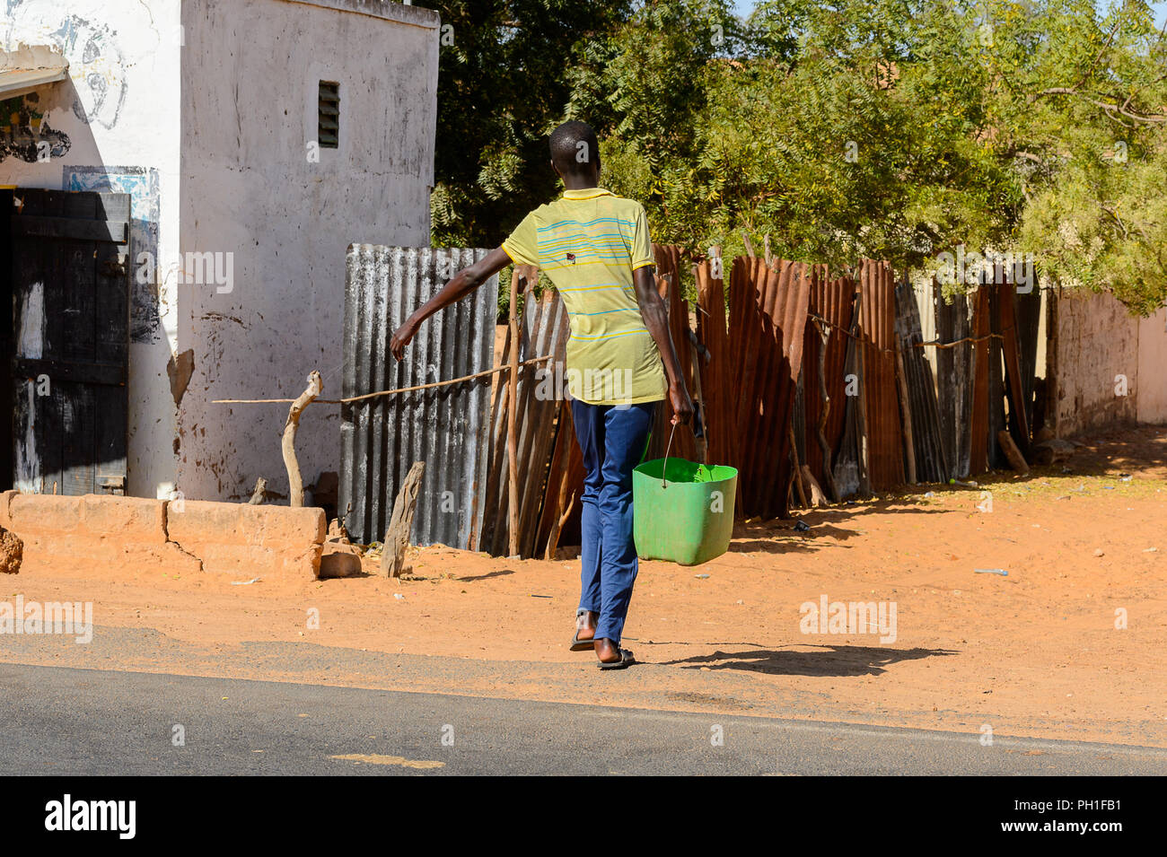 Deserto LAMPOUL village, SENEGAL - Apr 23, 2017: Non identificato uomo senegalese porta una benna di verde in un villaggio vicino al deserto Lampoul Foto Stock