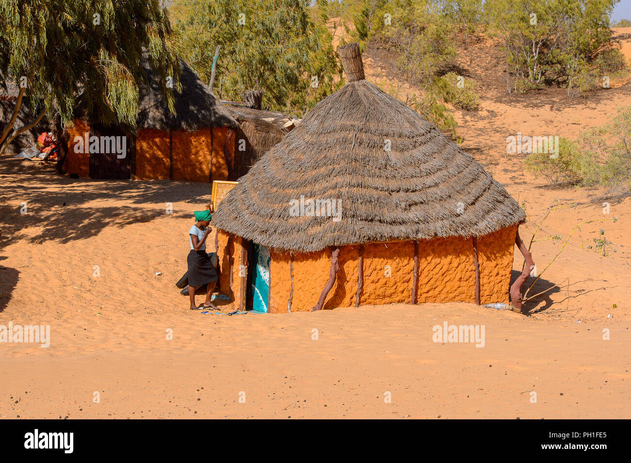 Deserto LAMPOUL, SENEGAL - Apr 23, 2017: Non identificato donna senegalese in velo di colore verde e la gonna nera sorge vicino la baracca in un deserto Lampoul, essere Foto Stock