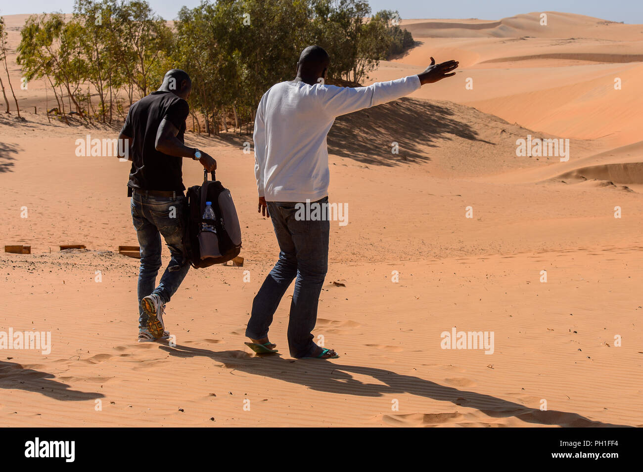 Deserto LAMPOUL, SENEGAL - Apr 23, 2017: Non identificato uomo senegalesi in camicia bianca si alza la mano in un deserto Lampoul, bellissimo paesaggio luogo Foto Stock