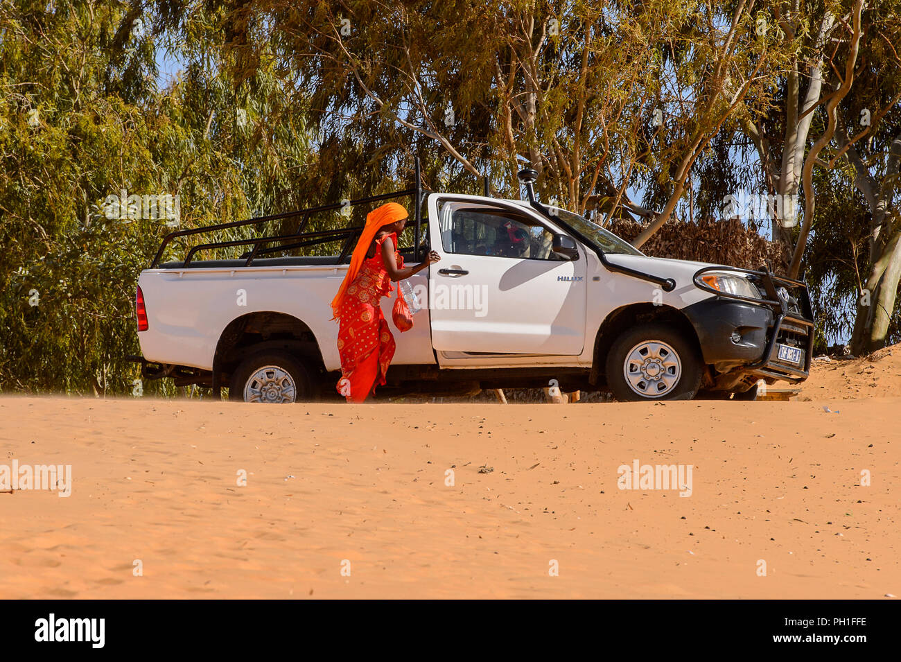 Deserto LAMPOUL, SENEGAL - Apr 23, 2017: Non identificato donna senegalese in abiti tradizionali passeggiate vicino la vettura in un deserto Lampoul, bella landsca Foto Stock