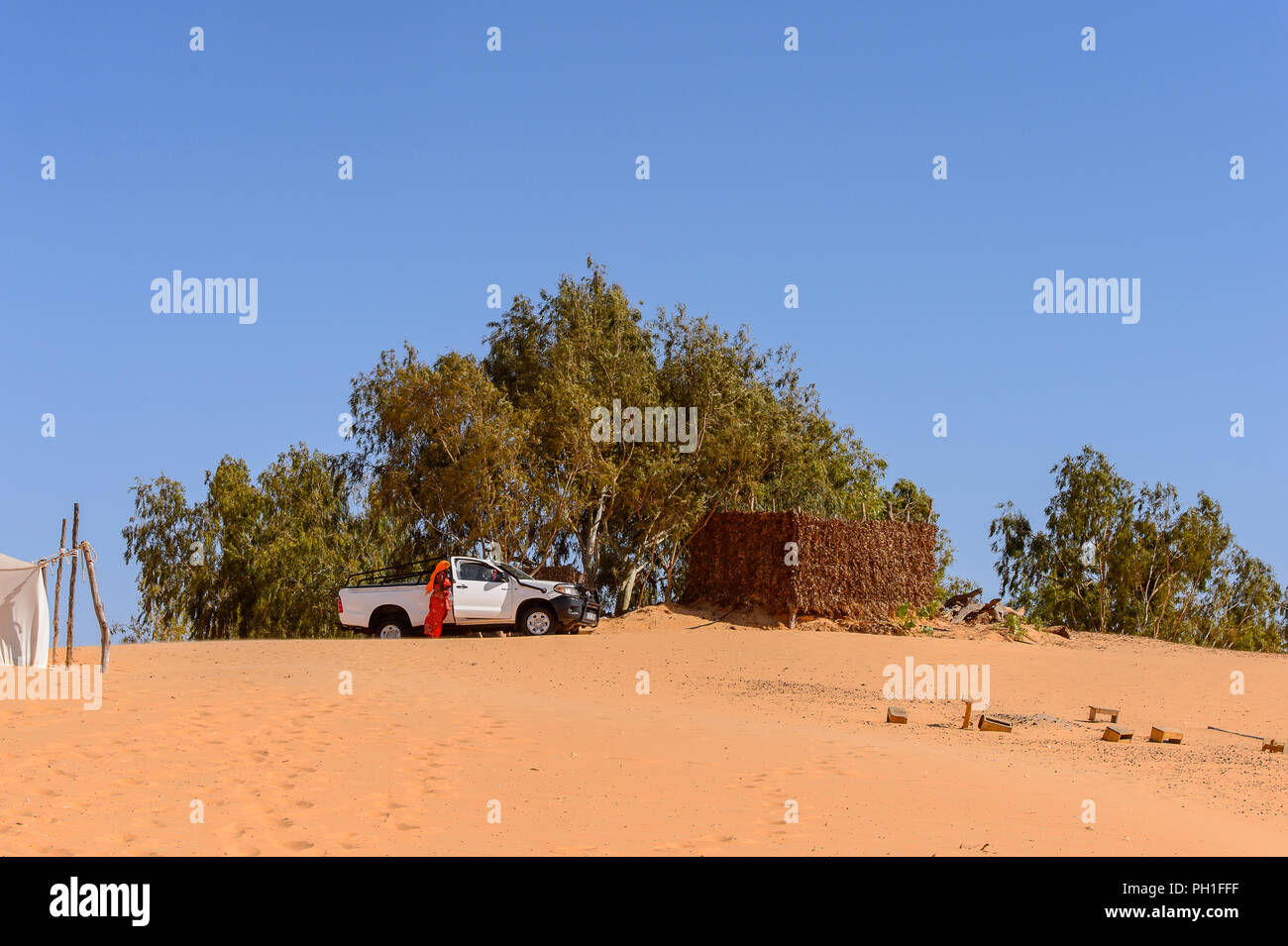 Deserto LAMPOUL, SENEGAL - Apr 23, 2017: Non identificato donna senegalese in abiti tradizionali passeggiate vicino la vettura in un deserto Lampoul, bella landsca Foto Stock