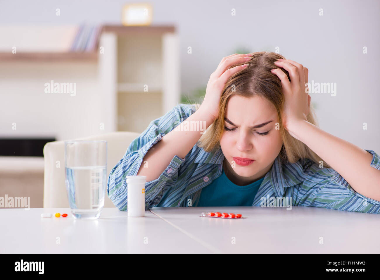 Donna di prendere le pillole per affrontare il dolore Foto Stock