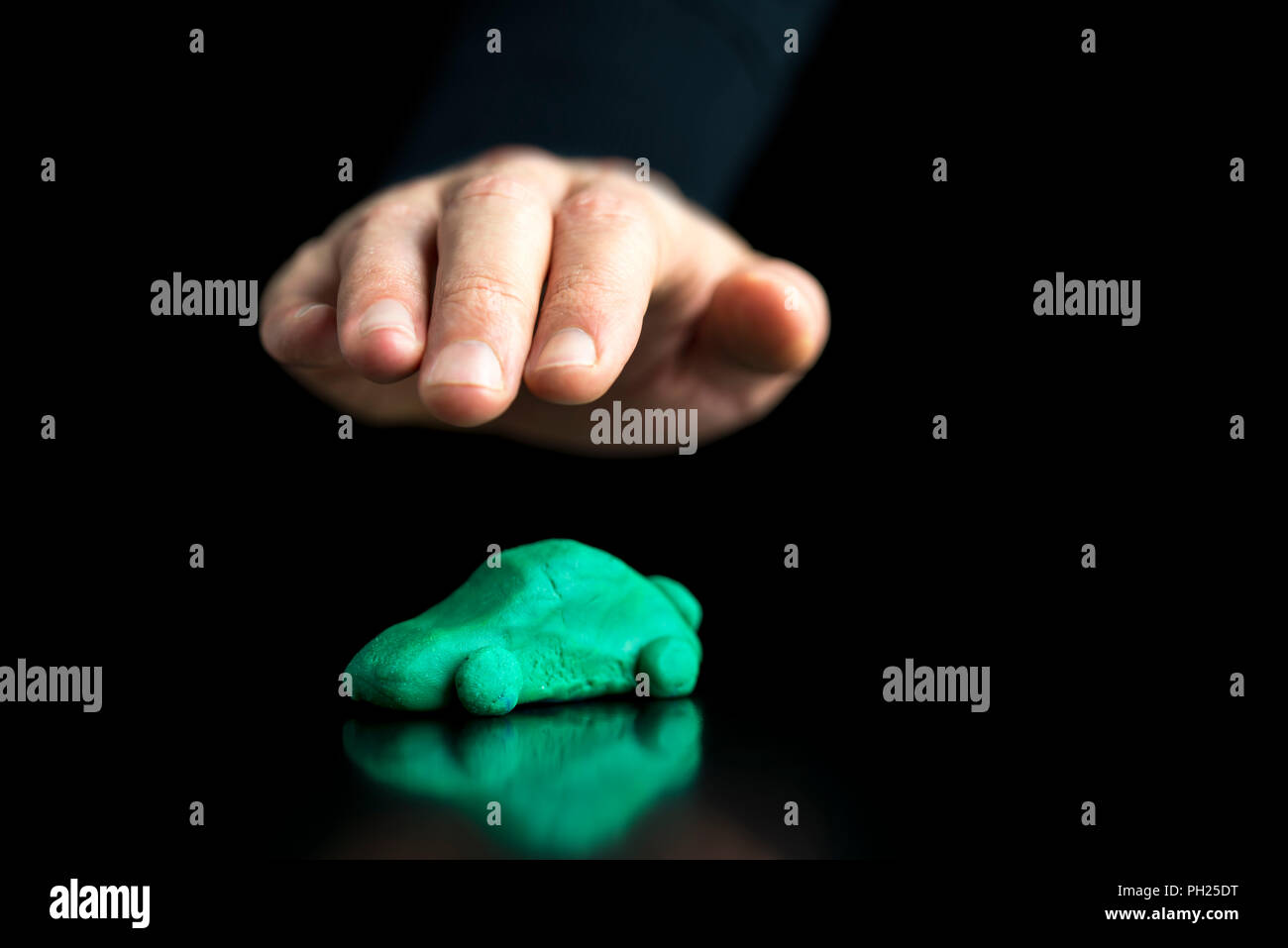 Immagine concettuale di un green o di un eco-friendly auto utilizzando del carburante alternativo per ridurre le emissioni di anidride carbonica e di inquinamento essendo protetto dalla mano di un busin Foto Stock