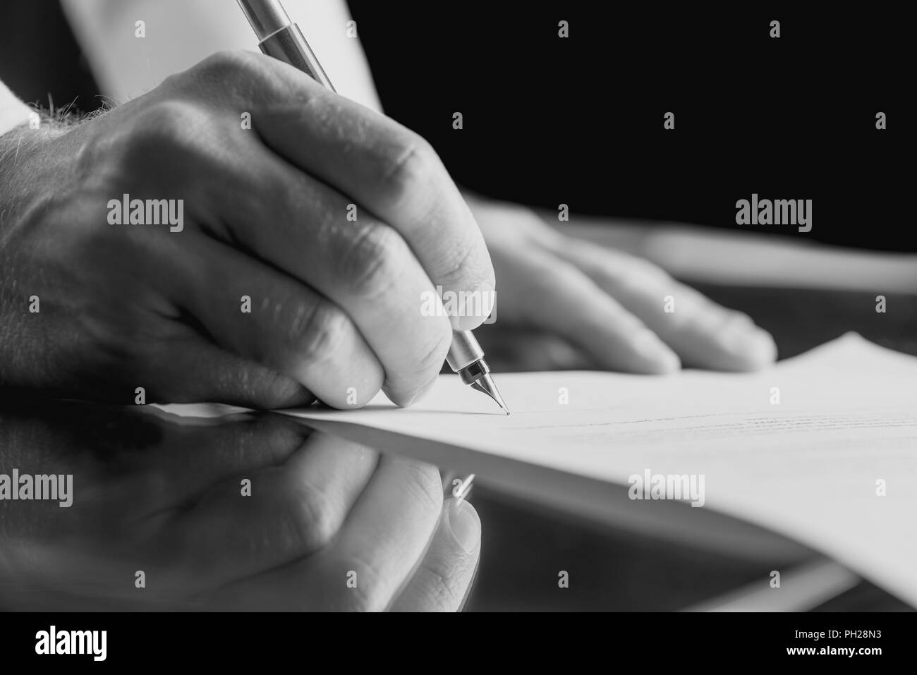 Chiudere monocromatica immagine in alto delle mani di un uomo d affari con la firma di un documento aziendale con una penna stilografica. Foto Stock