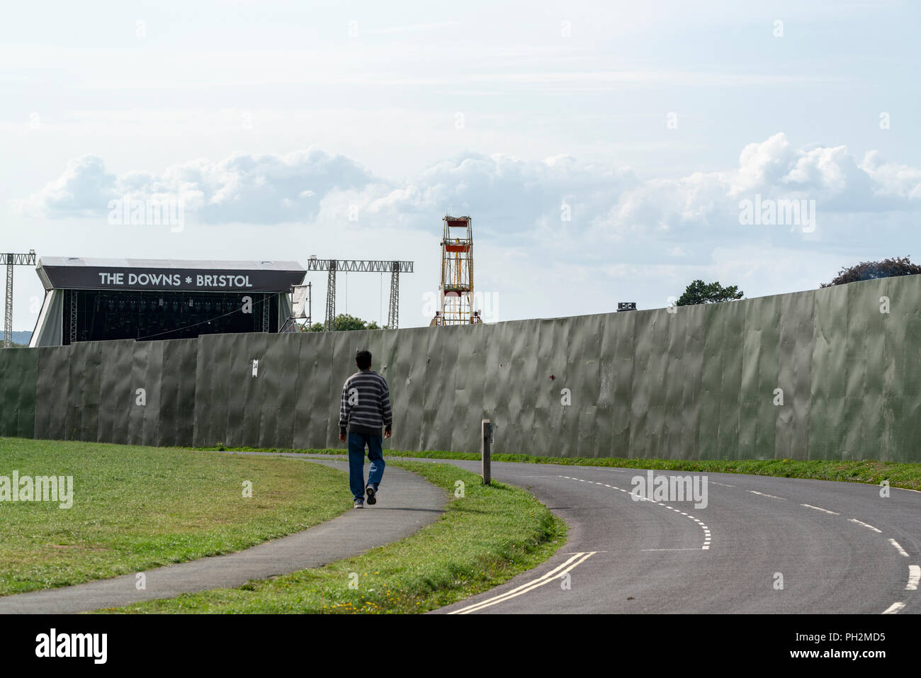 Bristol, Regno Unito, 30 Agosto, 2018: un uomo opinioni preparativi per il Downs, Bristol concerto come egli cammina oltre la barriera di protezione erette intorno al sito per l'evento. Il concerto all'aperto, un tasto attrezzatura in Bristol Summer calendario, è va in scena il 1 settembre, 2018. La manifestazione prevede musica da Noel Gallagher High flying uccelli e Paul Weller tra un pranzo line-up. Credito: mfimage/Alamy Live News Foto Stock