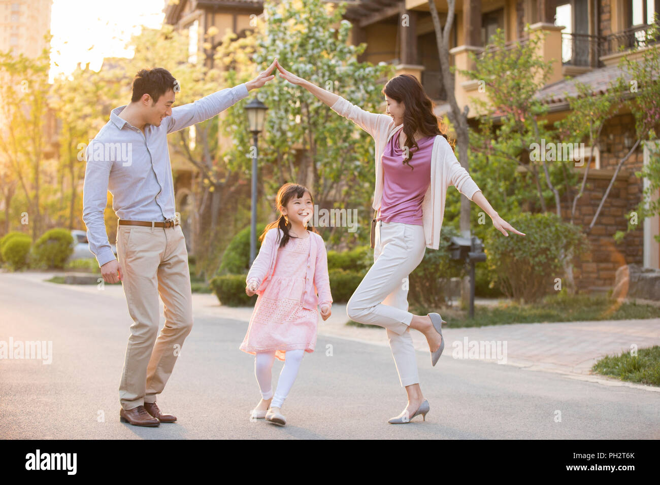 Felice famiglia giovane giocare davanti alla loro casa nuova Foto Stock
