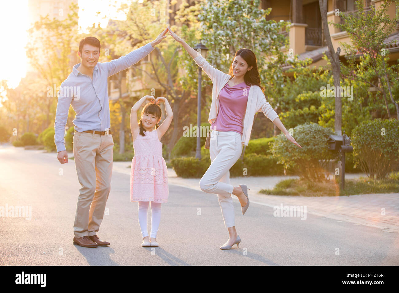 Felice famiglia giovane in piedi di fronte a loro nuova casa Foto Stock