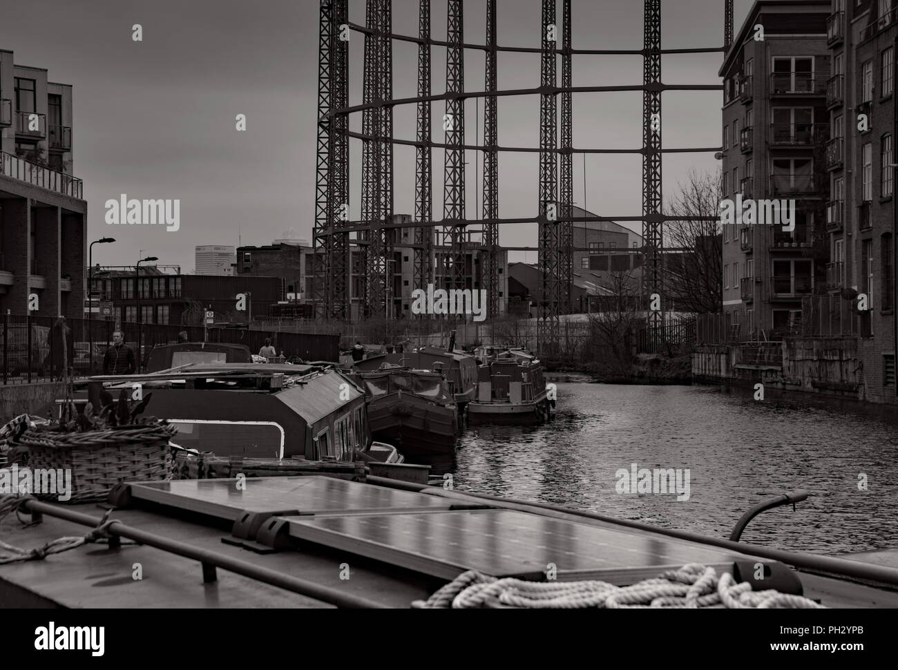 Barche del canale doppio ormeggiato a Haggerston sul Regents Canal non lontano da bethnal green. Sotto l'ombra del vuoto contenitore di gas. Foto Stock