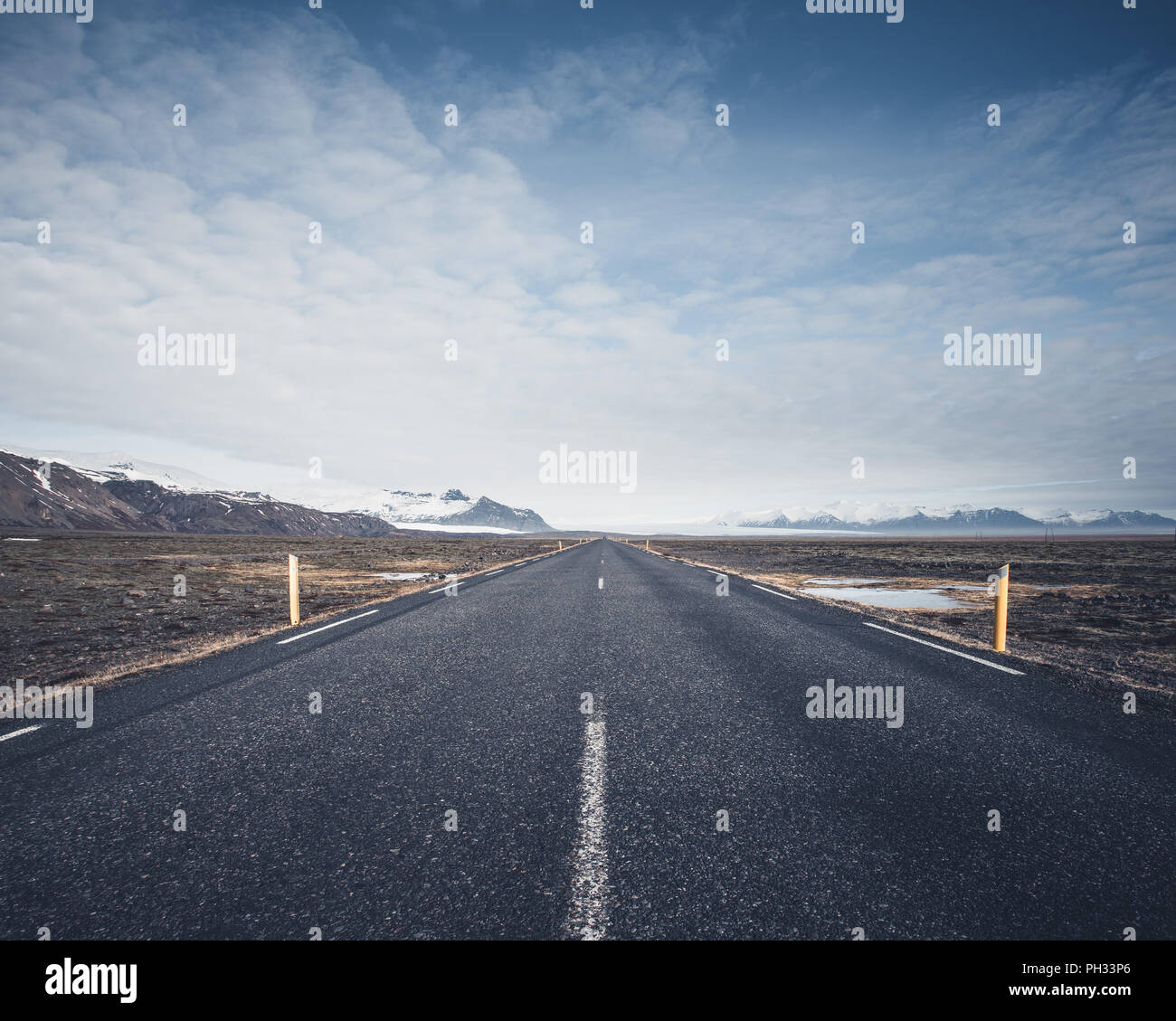 Strada che conduce verso le montagne nel vasto paesaggio aperto Foto Stock